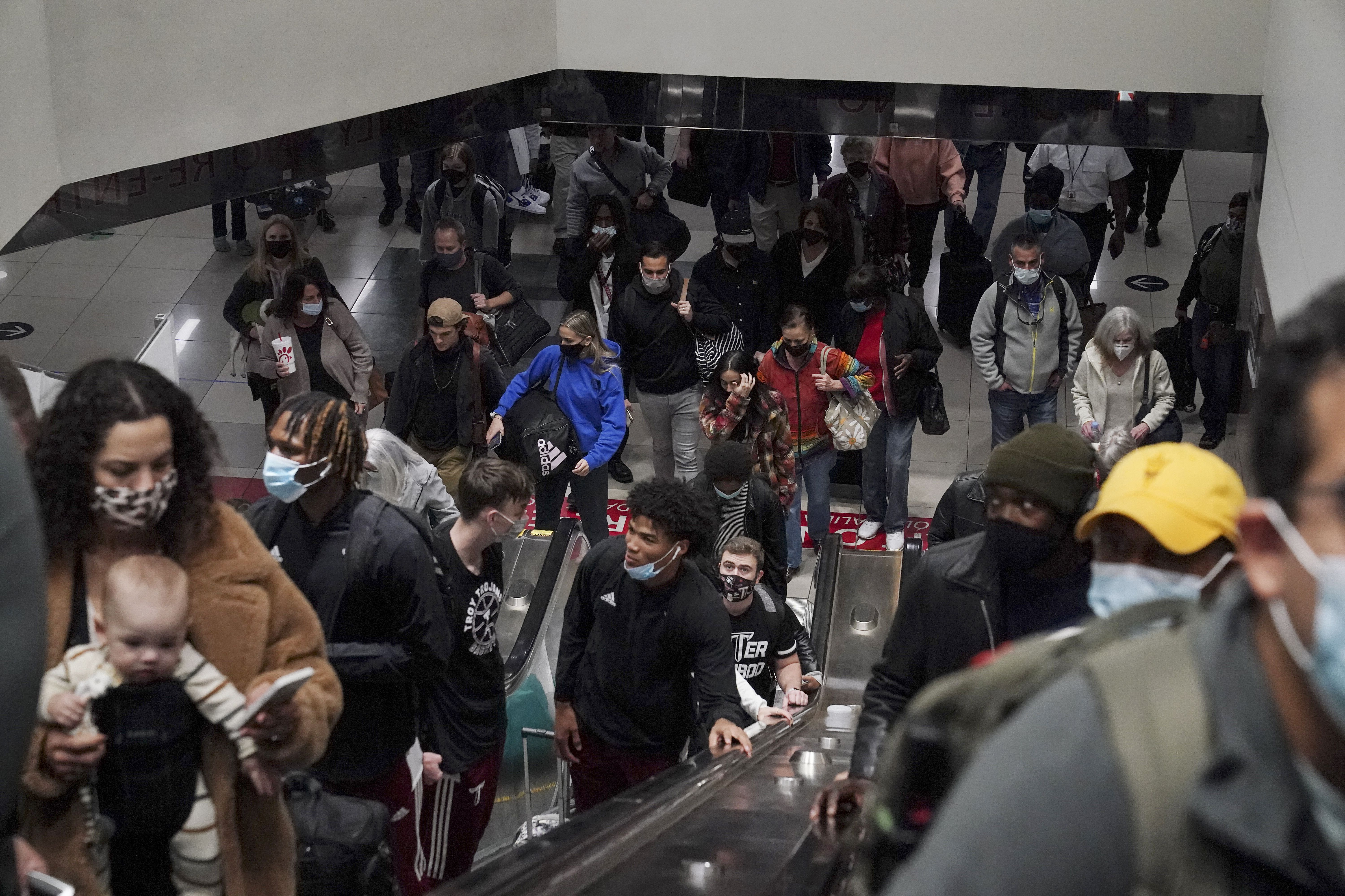 Travelers ride the escalator after their flight arrives at the Hartsfield-Jackson Atlanta International Airport on Tuesday, Nov. 23, 2021, in Atlanta. The Atlanta airport was once again named the busiest airport in the world.