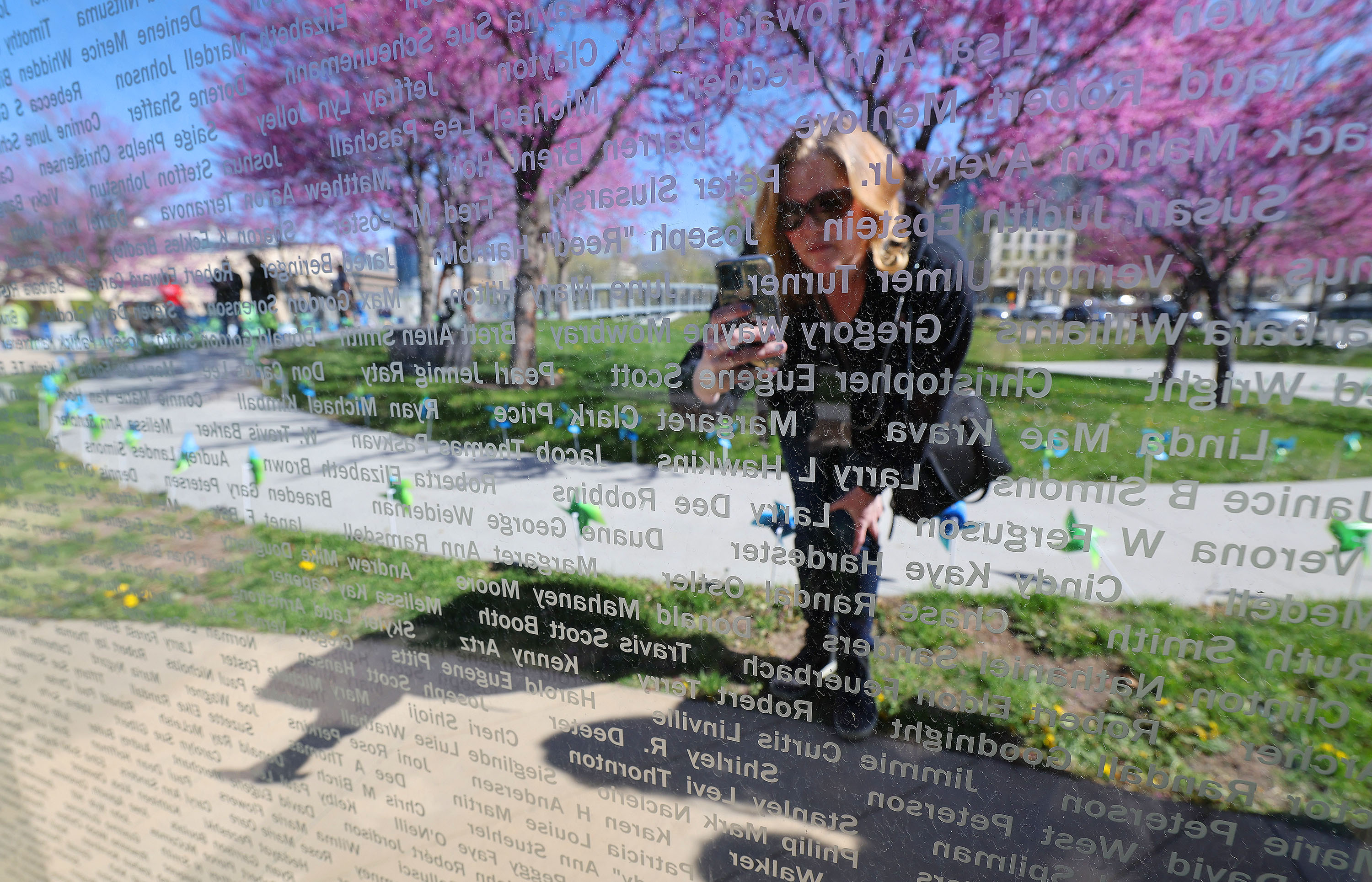 Annie Ableman takes a photo of her sister's name and donor Melissa Capener during National Donate Life Month and Donor Remembrance Day at the Celebration of Life Monument in Salt Lake City on Saturday.