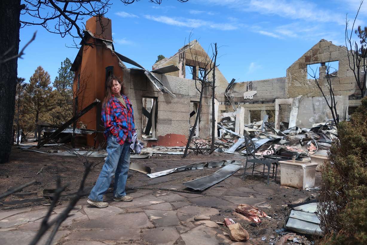Jeanne Welnick stands amid the ruins of her home on the outskirts of Flagstaff, Ariz., Thursday. A massive wildfire that started Easter Sunday burned about 30 square miles and more than a dozen homes, hopscotching across the parched landscape.