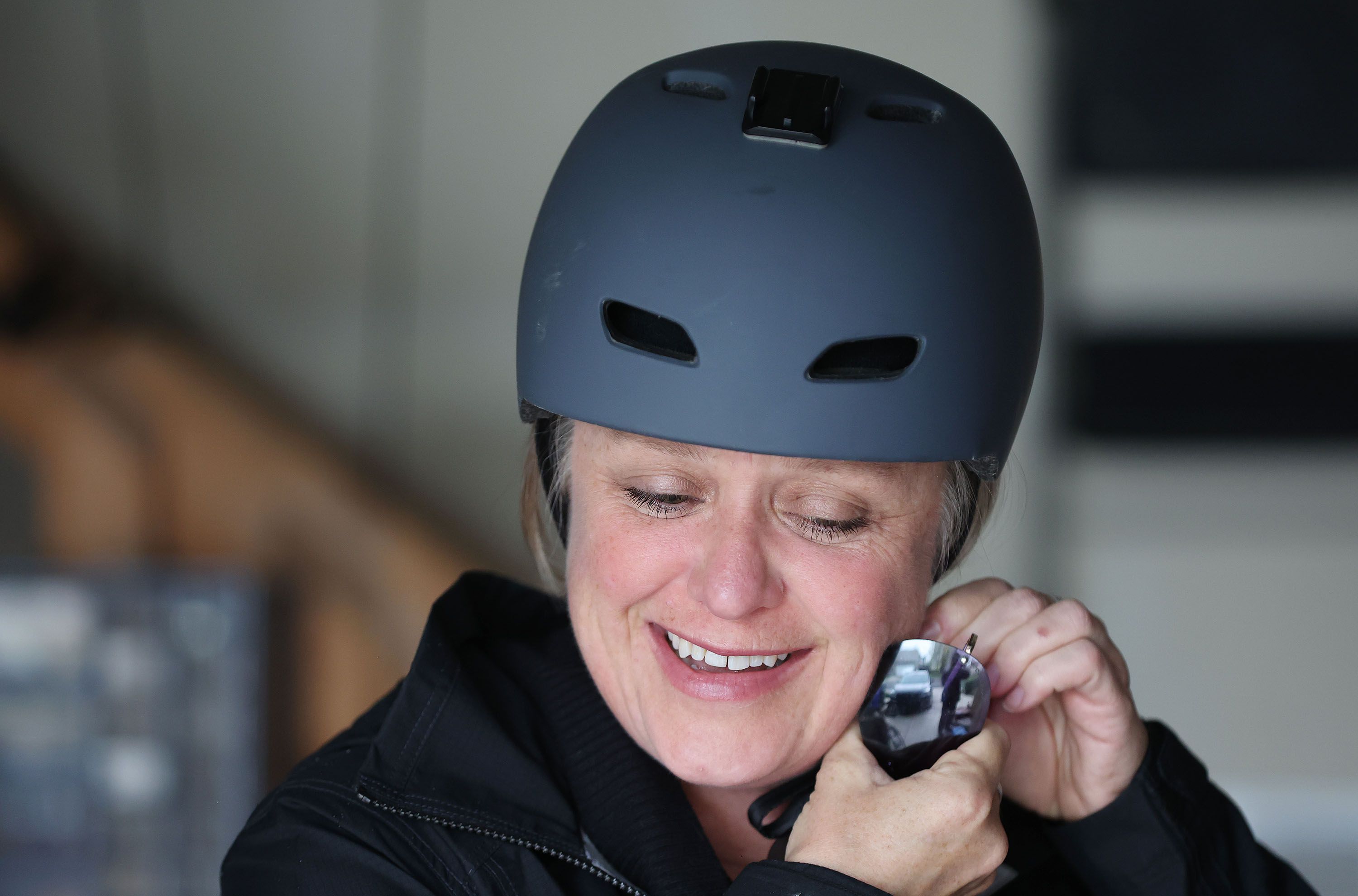 Jen Oxborrow straps on her helmet prior to riding her bicycle to work in Salt Lake City on Tuesday, May 3, 2022.