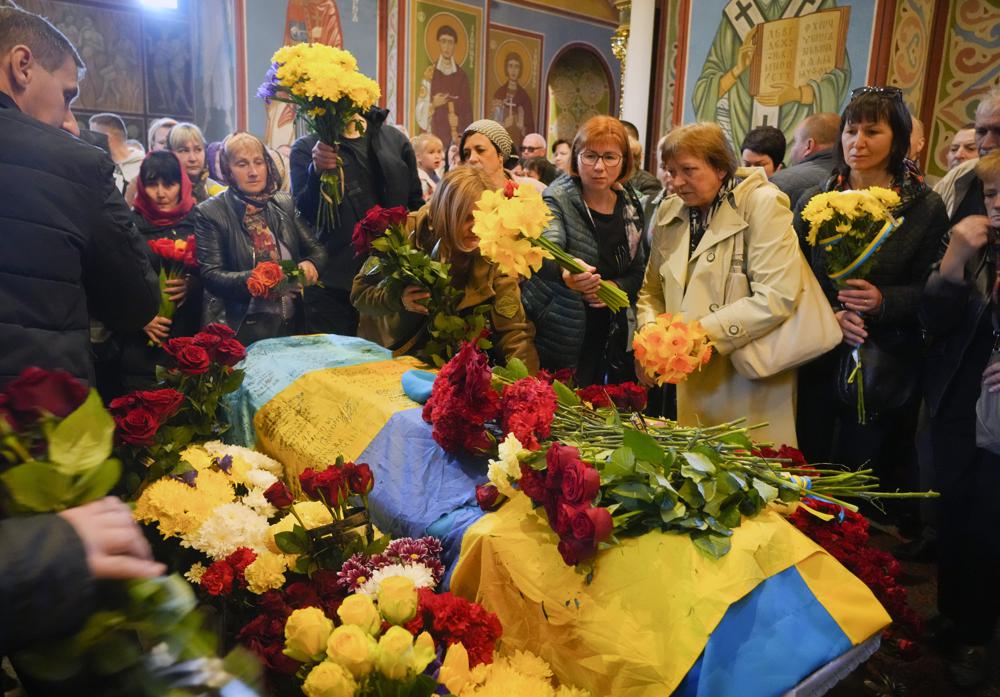 People pay their respects during the funeral ceremony for Ukrainian serviceman Ruslan Borovyk killed by the Russian troops in a battle in St. Michael cathedral. European Union moved to further punish Moscow for the war Wednesday by proposing a ban on oil imports.