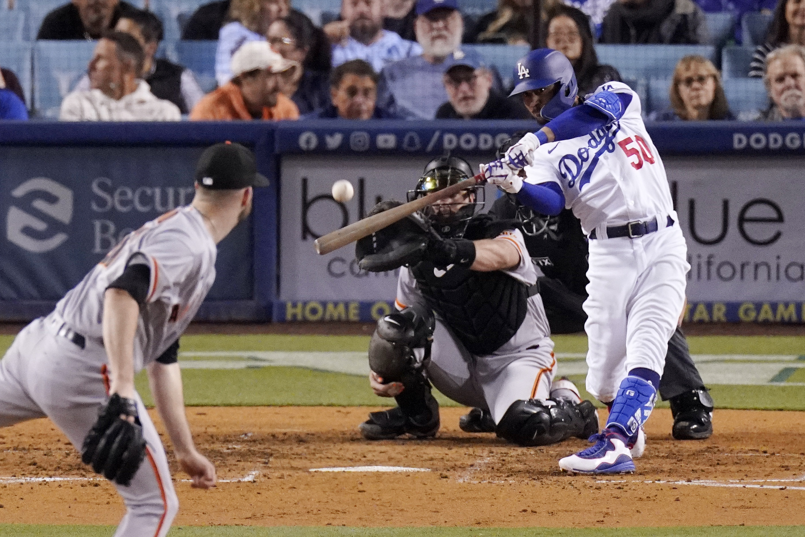 Los Angeles Dodgers right fielder Mookie Betts, right, hits a solo home run as San Francisco Giants starting pitcher Alex Wood, left, and catcher Joey Bart watch during the sixth inning of a baseball game Wednesday, May 4, 2022, in Los Angeles. 