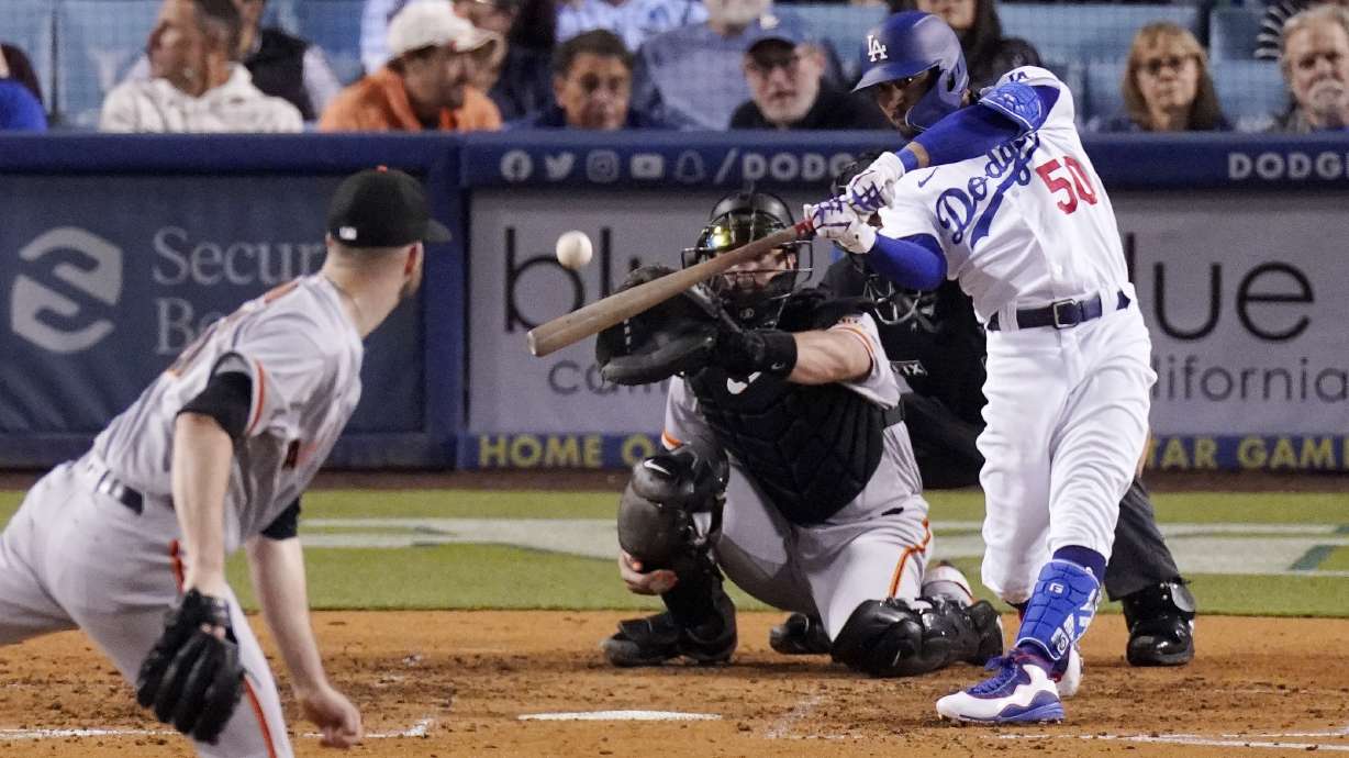 Los Angeles Dodgers right fielder Mookie Betts, right, hits a solo home run as San Francisco Giants starting pitcher Alex Wood, left, and catcher Joey Bart watch during the sixth inning of a baseball game Wednesday, May 4, 2022, in Los Angeles.