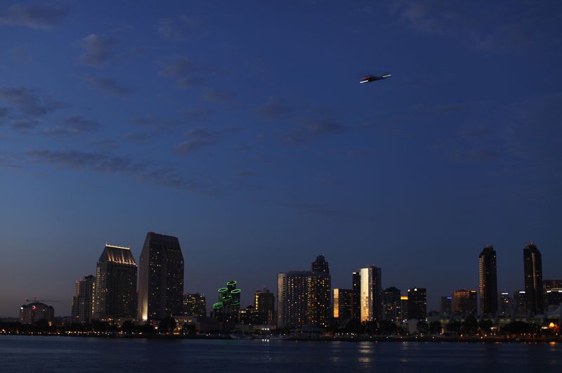 A military helicopter flies past the skyline of San Diego, Calif., Oct. 7, 2014. With more U.S. travelers expected to take to the skies and the roads this summer as COVID restrictions ease, unbridled demand is expected to strain capacity in the leisure and travel industry.