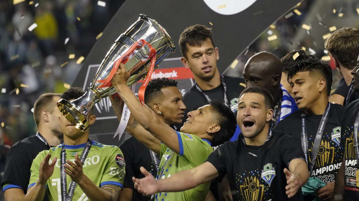 United States' Seattle Sounders forward Raul Ruidiaz holds the trophy alongside teammate midfielder Nicolás Lodeiro after the Sounders defeated Mexico's Pumas to win the CONCACAF Champions League soccer final Wednesday, May 4, 2022, in Seattle.