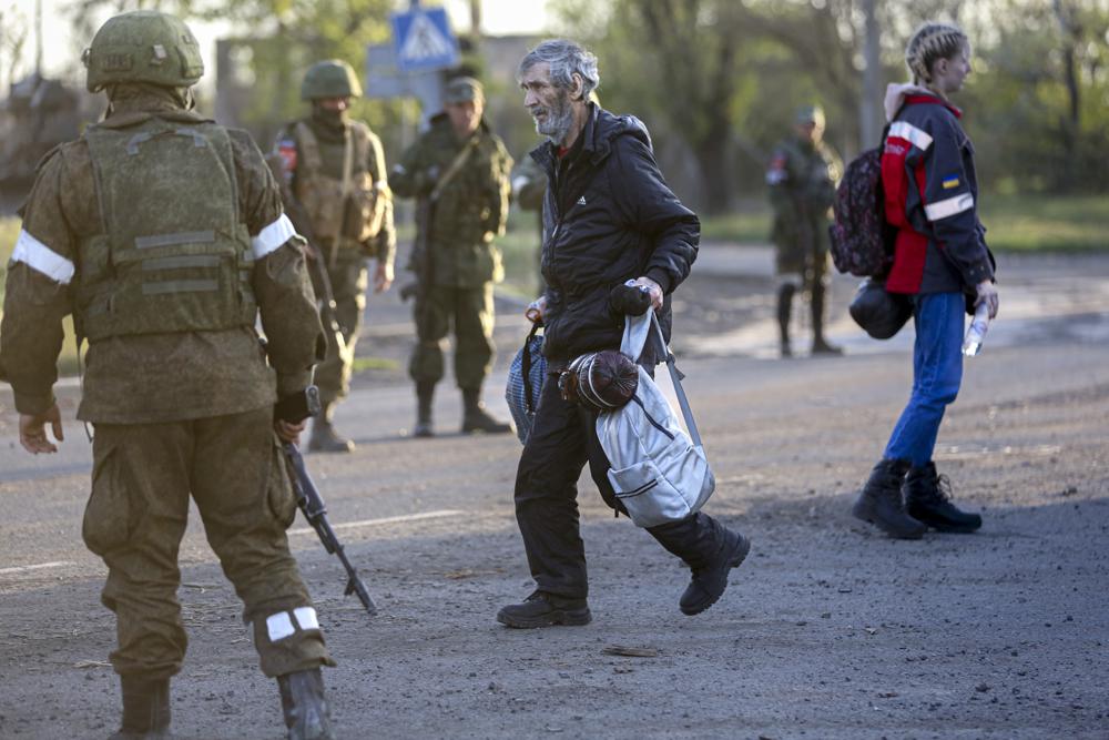 A man, who left a shelter in the Metallurgical Combine Azovstal walks to a bus between servicemen of the Russian Army and Donetsk People’s Republic militia in Mariupol, in territory under the government of the Donetsk People’s Republic, eastern Ukraine, Friday.
