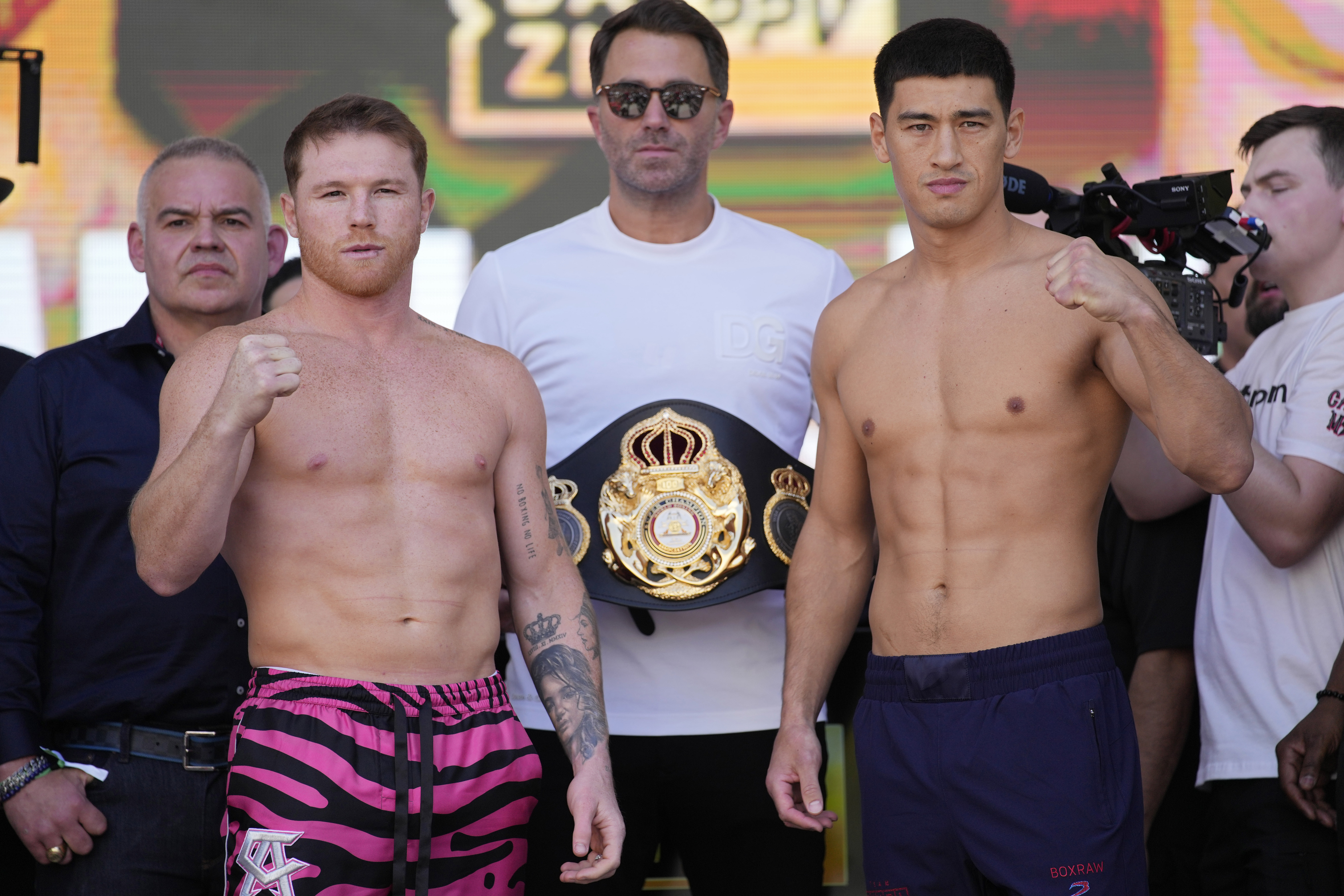 Canelo Alvarez, left, and Dmitry Bivol, right, pose next to promoter Eddie Hearn during a ceremonial weigh-in for their Saturday boxing fight, Friday, May 6, 2022, in Las Vegas. 