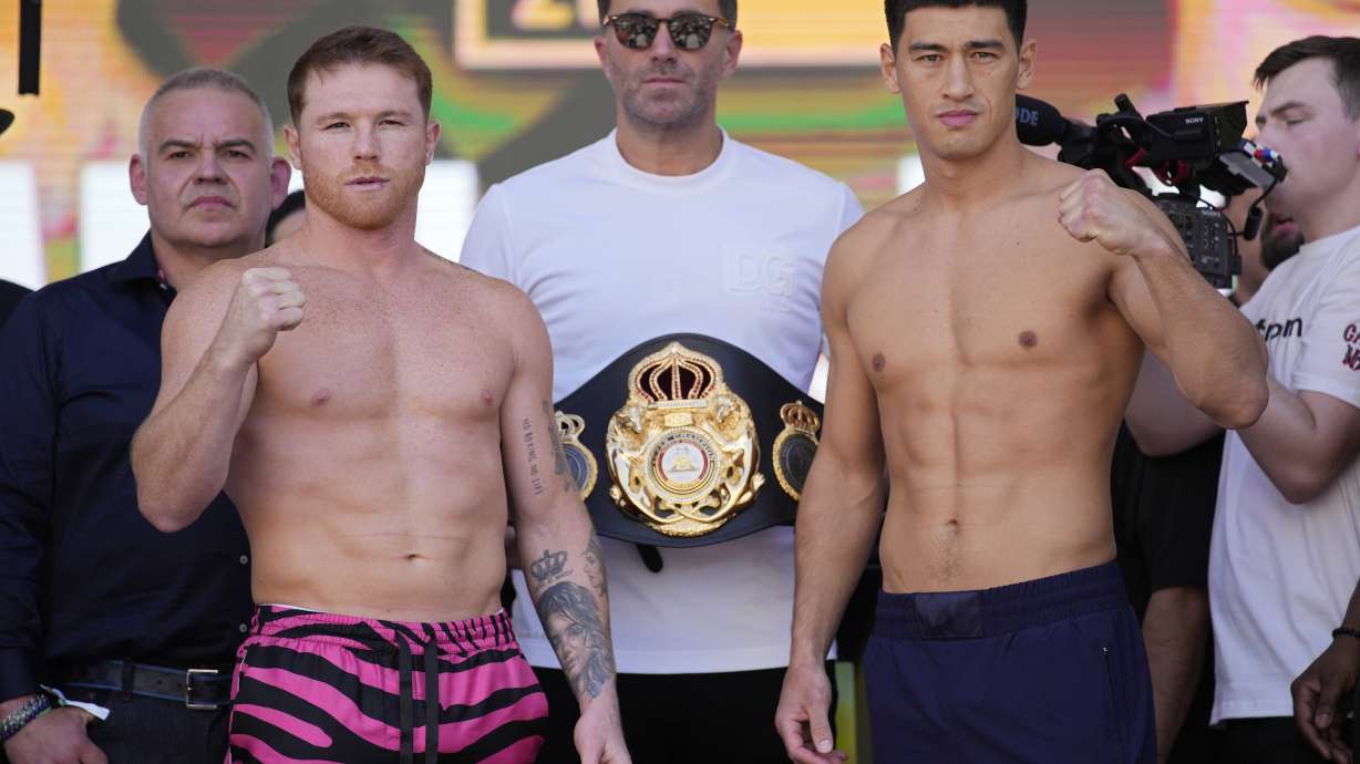 Canelo Alvarez, left, and Dmitry Bivol, right, pose next to promoter Eddie Hearn during a ceremonial weigh-in for their Saturday boxing fight, Friday, May 6, 2022, in Las Vegas.