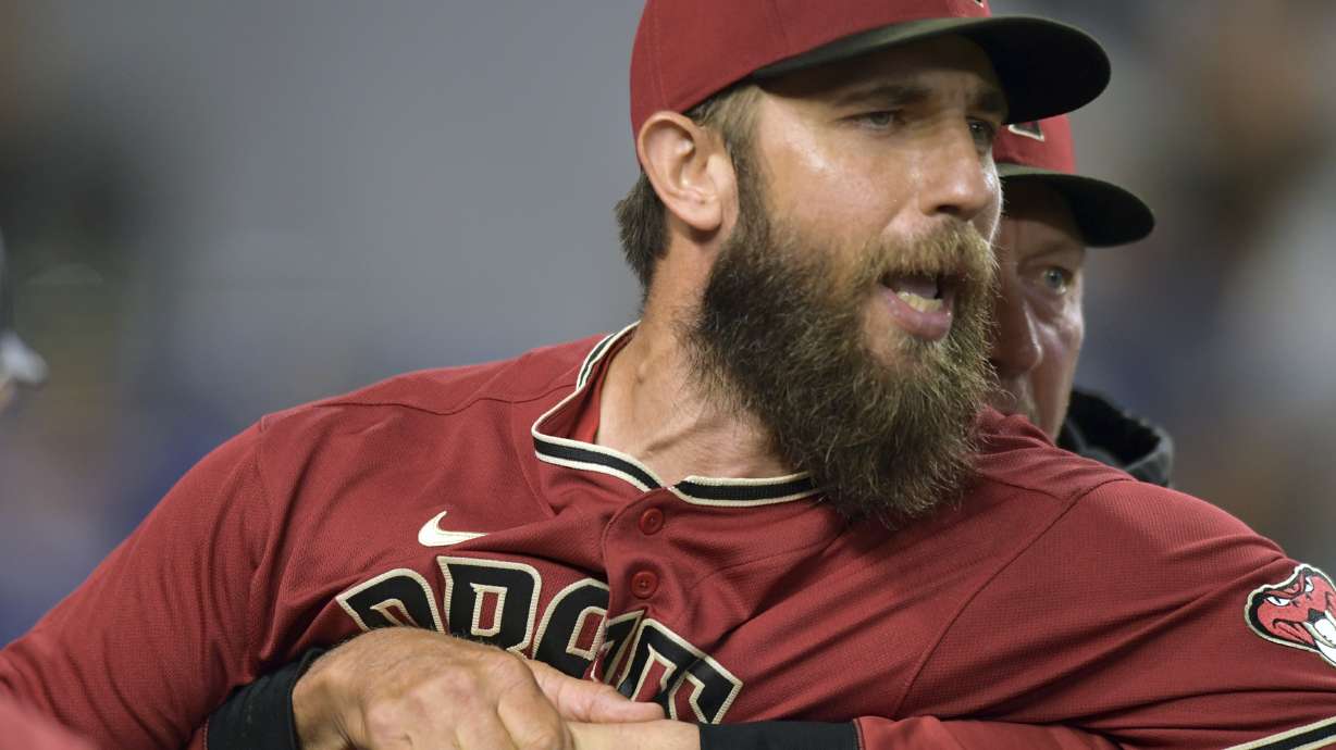 Arizona Diamondbacks' pitcher Madison Bumgarner, left, is restrained by bench coach Jeff Banister while arguing with umpires after the first inning of a baseball game against the against the Miami Marlins, Wednesday, May 4, 2022, in Miami.