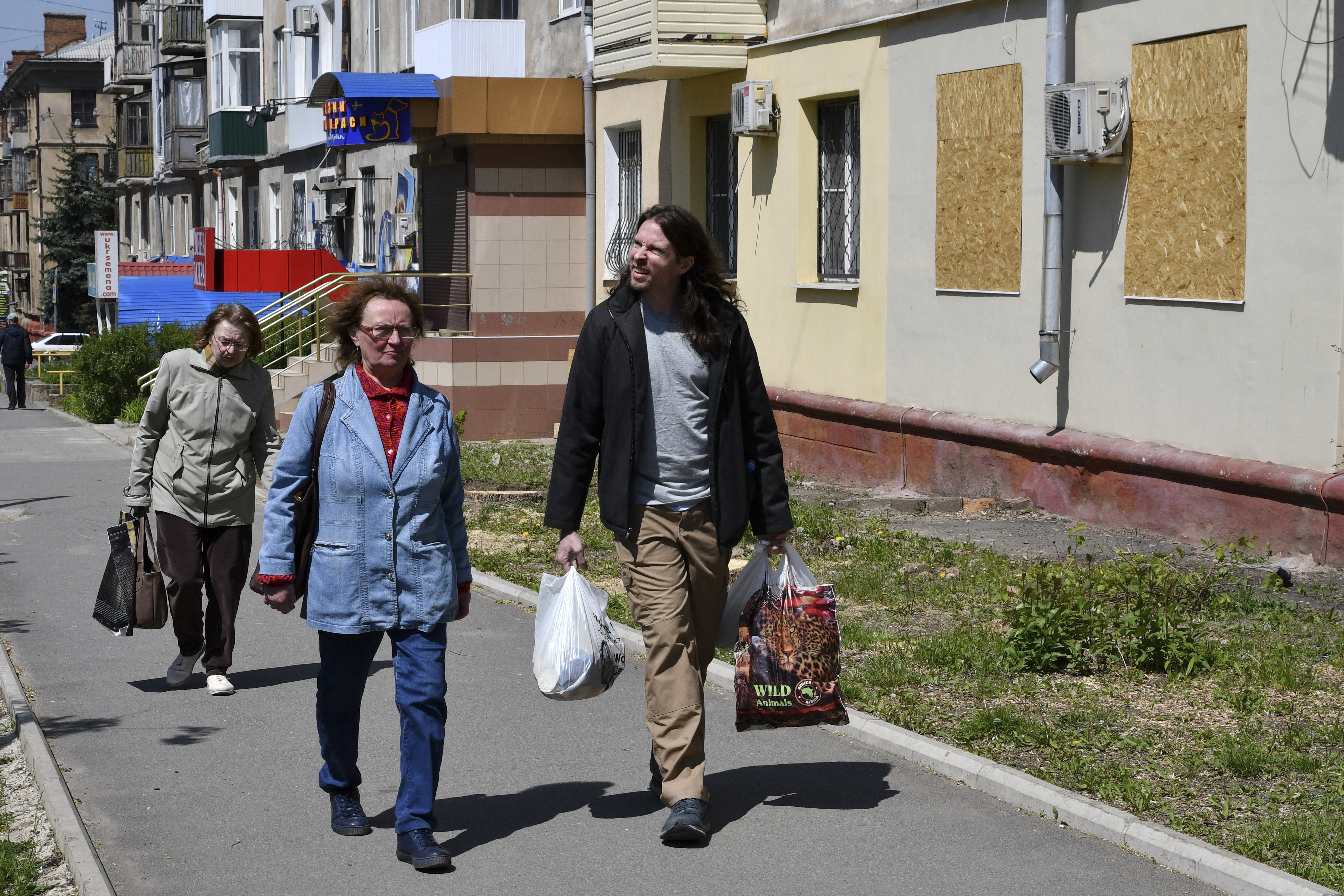 Patrick Michael Jones, 34, a volunteer from Houston, helps Ukrainian women Vera, 59, center, and Lilia, 55, to carry humanitarian aid in Kramatorsk, Ukraine, Friday. Jones came to Ukraine to help people in their difficult situation. He worked as a salesman at a gun store in Houston.