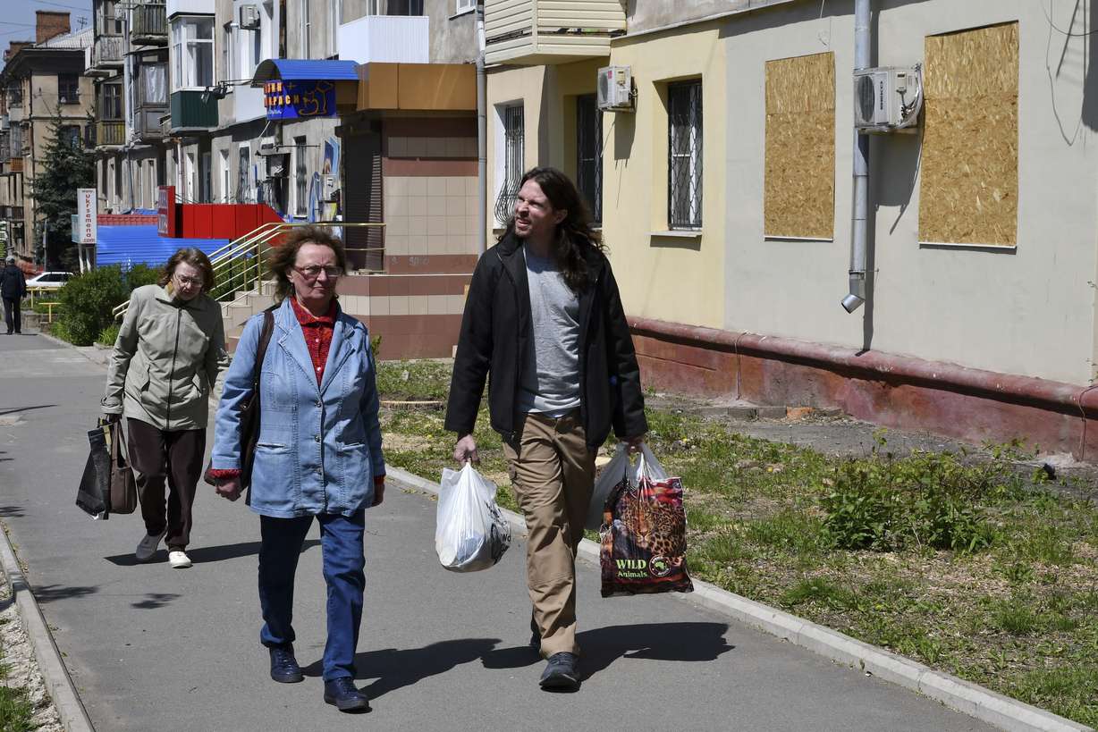 Patrick Michael Jones, 34, a volunteer from Houston, helps Ukrainian women Vera, 59, center, and Lilia, 55, to carry humanitarian aid in Kramatorsk, Ukraine, Friday. Jones came to Ukraine to help people in their difficult situation. He worked as a salesman at a gun store in Houston.