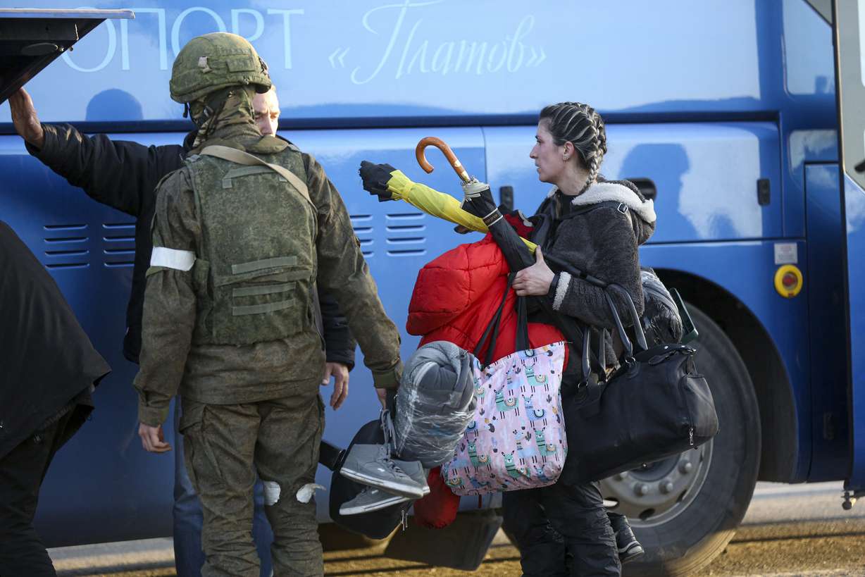 A woman who left a shelter in the Metallurgical Combine Azovstal walks to a bus escorted by a serviceman of Donetsk People's Republic militia in Mariupol, in territory under the government of the Donetsk People's Republic, eastern Ukraine, Friday.