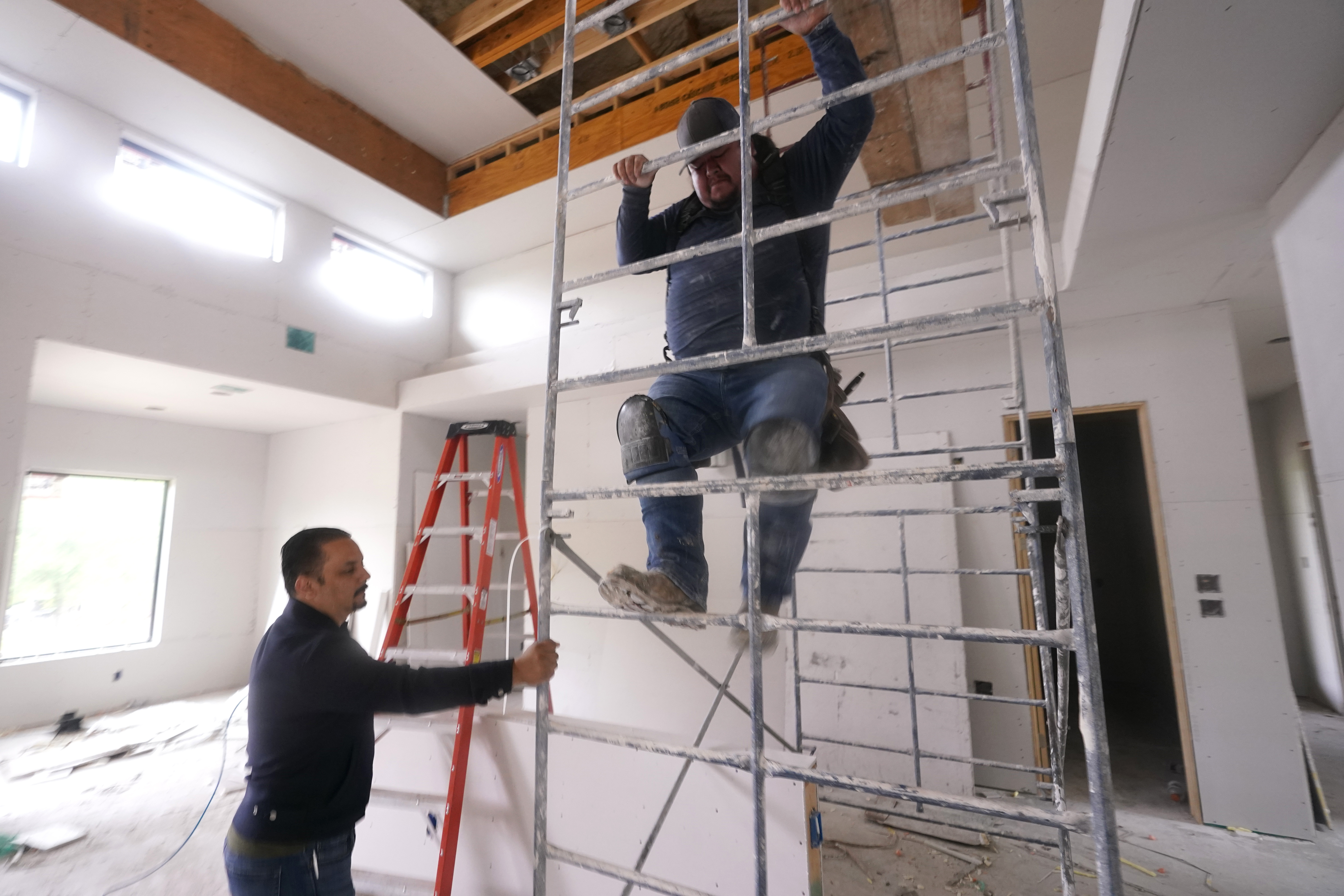 Joshua Correa, left, steadies a scaffolding for Samuel as they work at a home under construction in Plano, Texas, on May 3. There are an estimated 2 million fewer immigrants than expected in the United States, helping fuel a desperate scramble for workers in many sectors that is also contributing to shortages and price increases. 