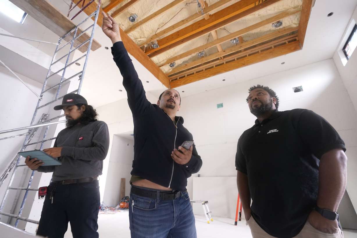 Homebuilder Joshua Correa, center, along with his son Josh Correa, left, point out details to cabinet subcontractor Winston Grosvenor at a home under construction in Plano, Texas, Tuesday. Correa has struggled to hire supervisors for his work sites, with immigrant job candidates demanding $100,000 yearly pay.