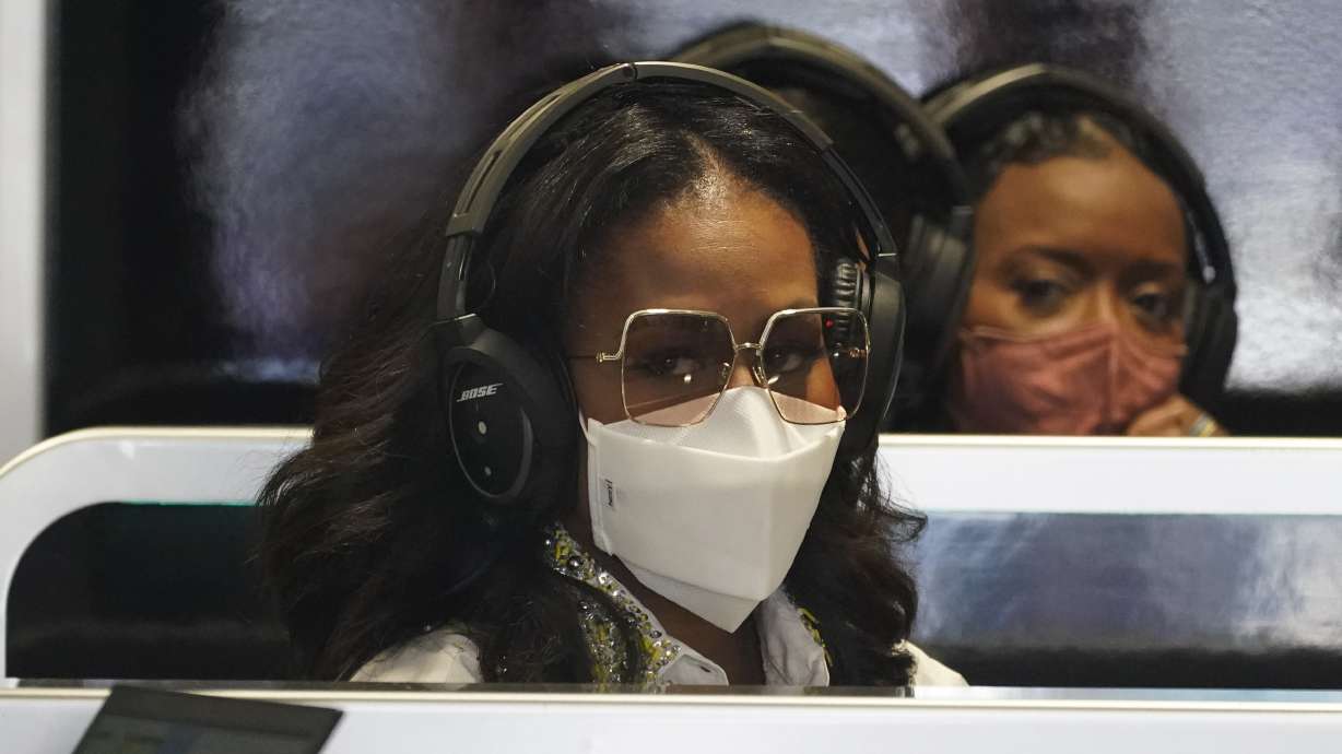 Former First Lady Michelle Obama, left, sits in the Mercedes team garage before the third practice session for the Formula One Miami Grand Prix auto race at the Miami International Autodrome, Saturday, May 7, 2022, in Miami Gardens, Fla.