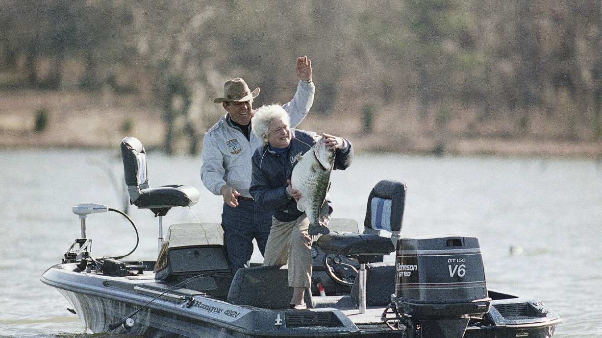 FILE - First lady Barbara Bush holds a mounted bass as a joke with fishing partner Ray Scott at his lake in Pintlala, Ala., on Jan. 1, 1990. A longtime aide said Scott died on Sunday, May 8, 2022, at the age of 88.