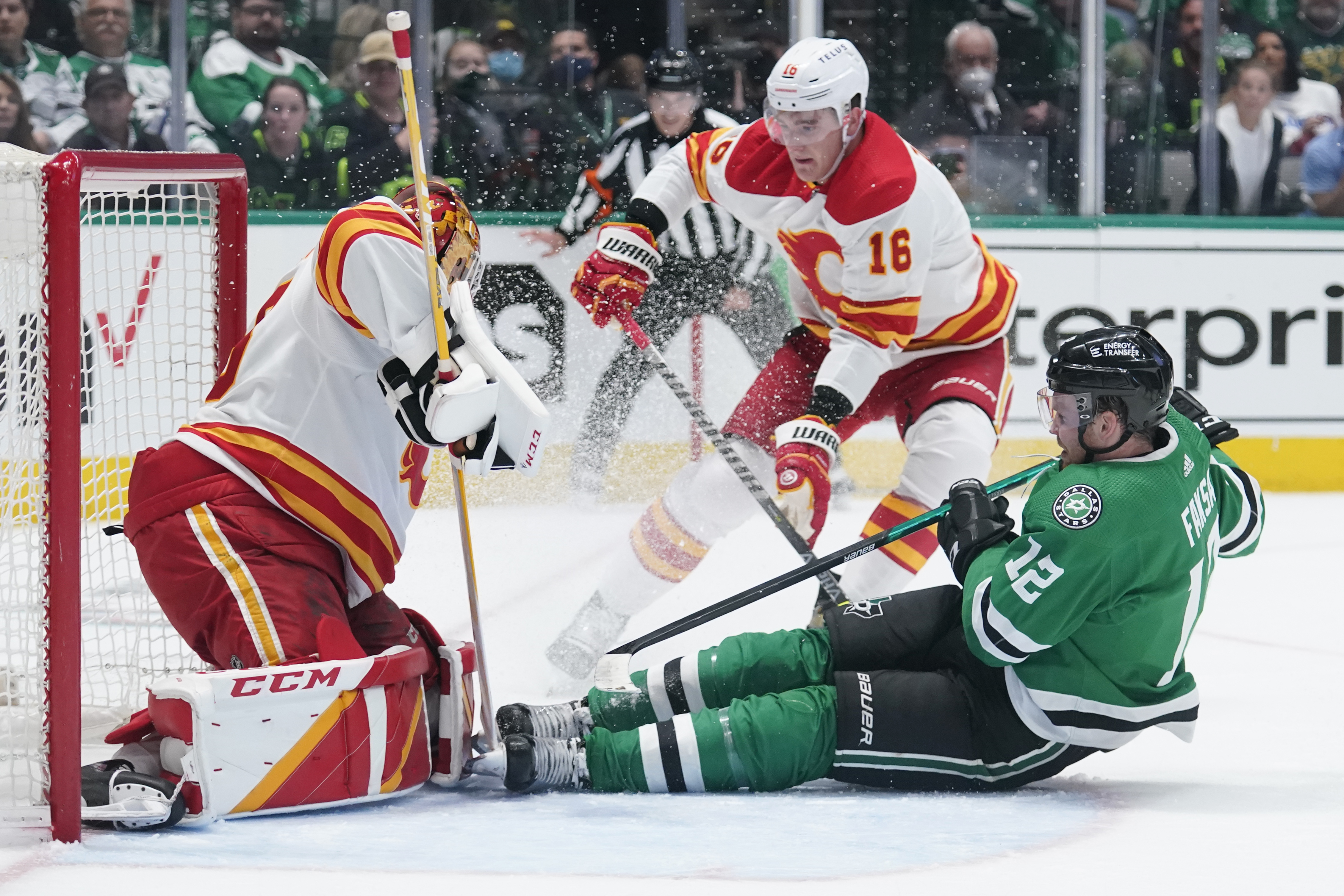 Dallas Stars center Radek Faksa (12) slides into Calgary Flames goaltender Jacob Markstrom, left, following a shot in the first period of Game 4 of an NHL hockey Stanley Cup first-round playoff series, Monday, May 9, 2022, in Dallas. Flames Nikita Zadorov is at center. 