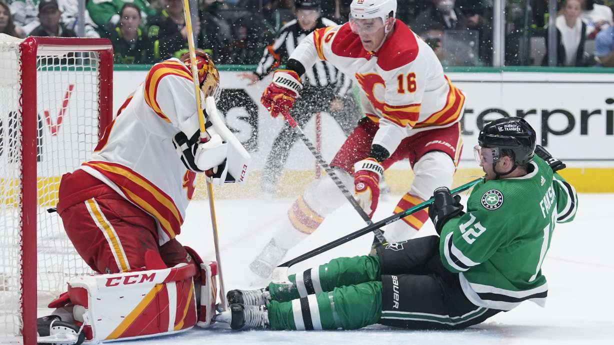 Dallas Stars center Radek Faksa (12) slides into Calgary Flames goaltender Jacob Markstrom, left, following a shot in the first period of Game 4 of an NHL hockey Stanley Cup first-round playoff series, Monday, May 9, 2022, in Dallas. Flames Nikita Zadorov is at center.