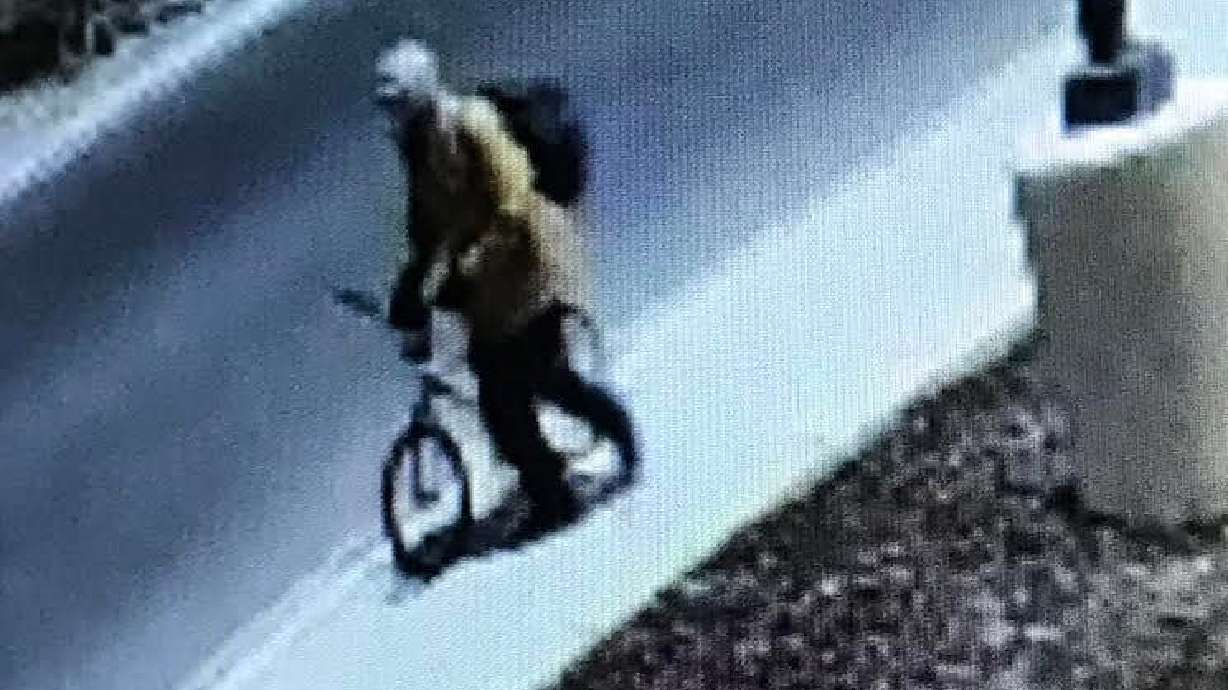 On Wednesday, South Salt Lake police announced they were looking for a person whose image was captured in surveillance footage at the scene. The blurry photo shows a person wearing a tan-colored jacket or shirt, a hoodie or helmet and a dark-colored backpack, and walking with a bicycle.