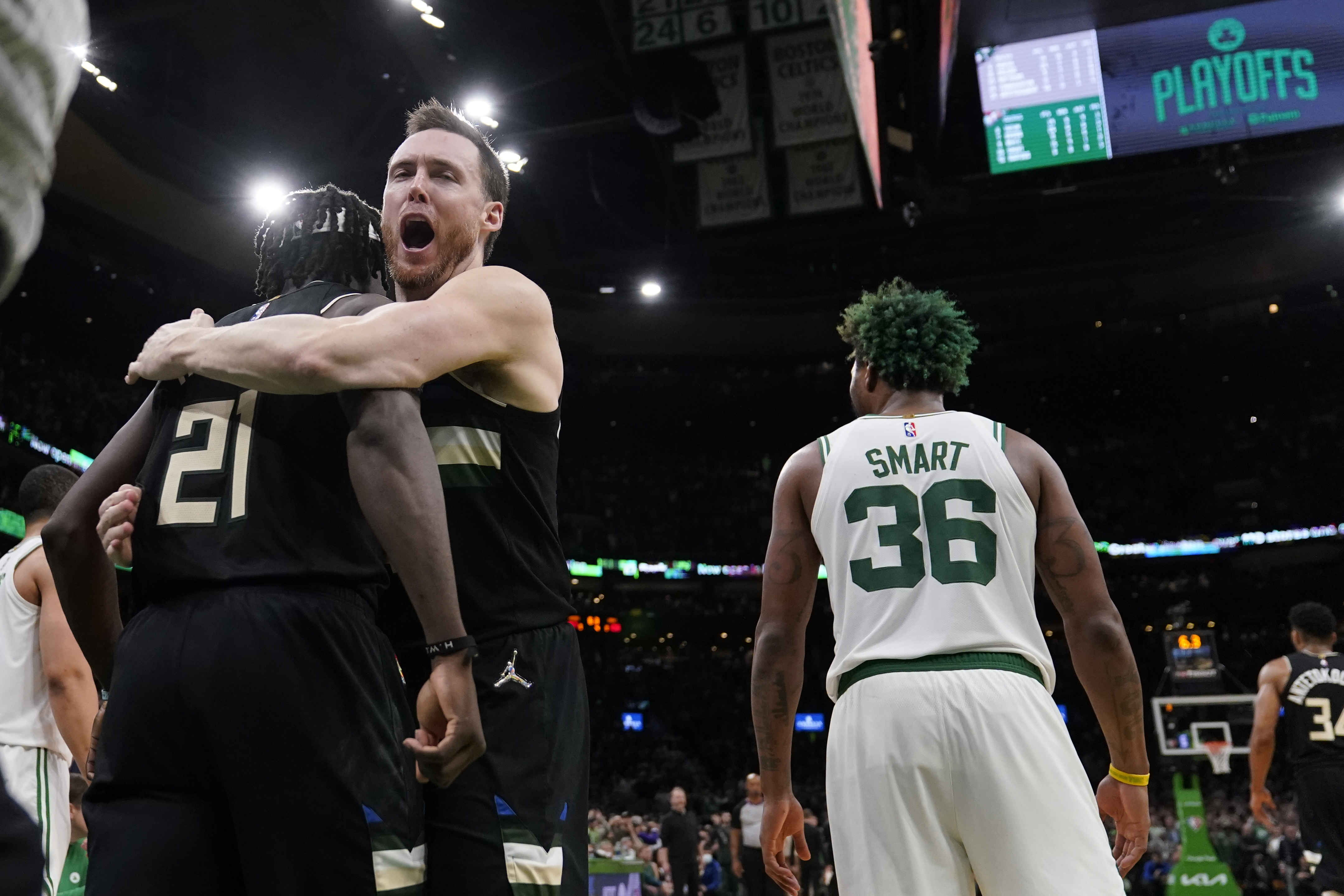 Milwaukee Bucks guard Jrue Holiday (21) is embraced by Pat Connaughton while celebrating after blocking a shot by Boston Celtics guard Marcus Smart (36) in the final seconds of play during the second half of Game 5 of an Eastern Conference semifinal in the NBA basketball playoffs, Wednesday, May 11, 2022, in Boston. The Bucks won 110-107. 