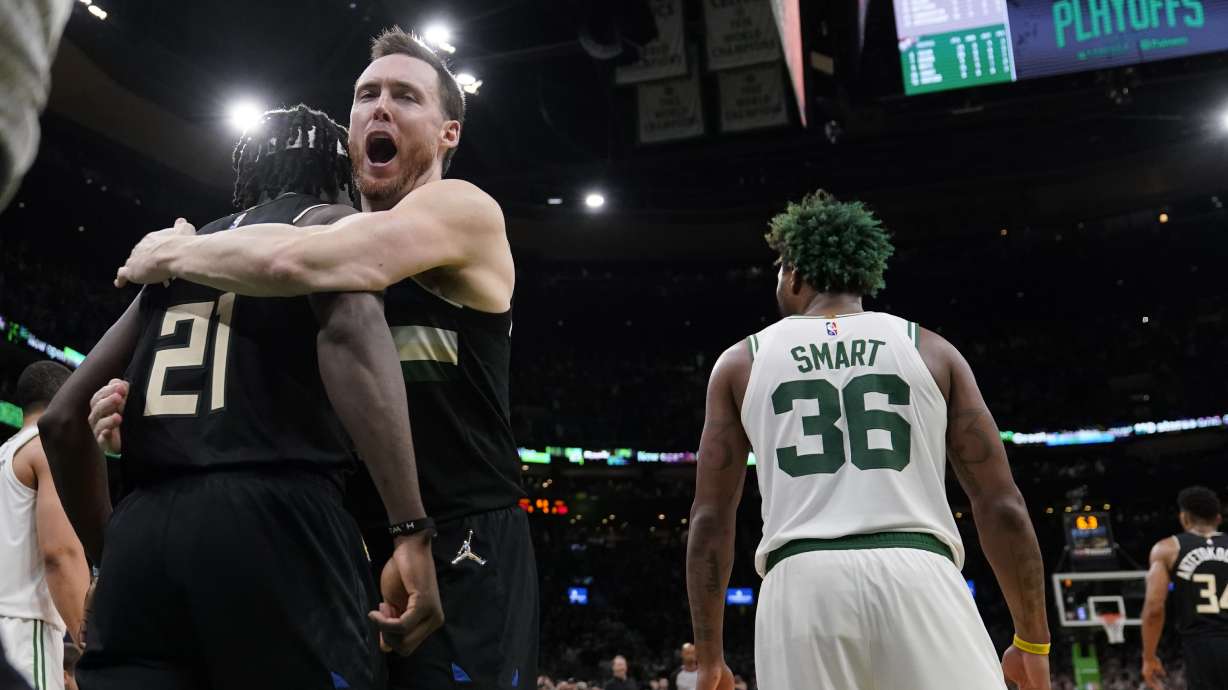 Milwaukee Bucks guard Jrue Holiday (21) is embraced by Pat Connaughton while celebrating after blocking a shot by Boston Celtics guard Marcus Smart (36) in the final seconds of play during the second half of Game 5 of an Eastern Conference semifinal in the NBA basketball playoffs, Wednesday, May 11, 2022, in Boston. The Bucks won 110-107.