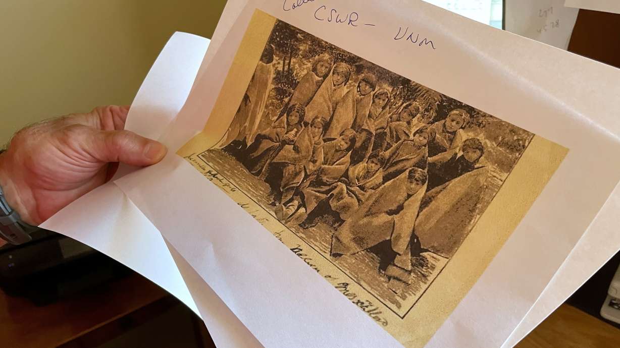 In this July 8, 2021, photo, adjunct history professor Larry Larrichio holds a copy of a late 19th century photograph of pupils at an Indigenous boarding school in Santa Fe, N.M. A new Department of the Interior report says the government provided support to religious boarding schools for Native children in the 19th and early 20th centuries to an extent that normally would have been prohibited by bans on the use of federal funds for religious schools.