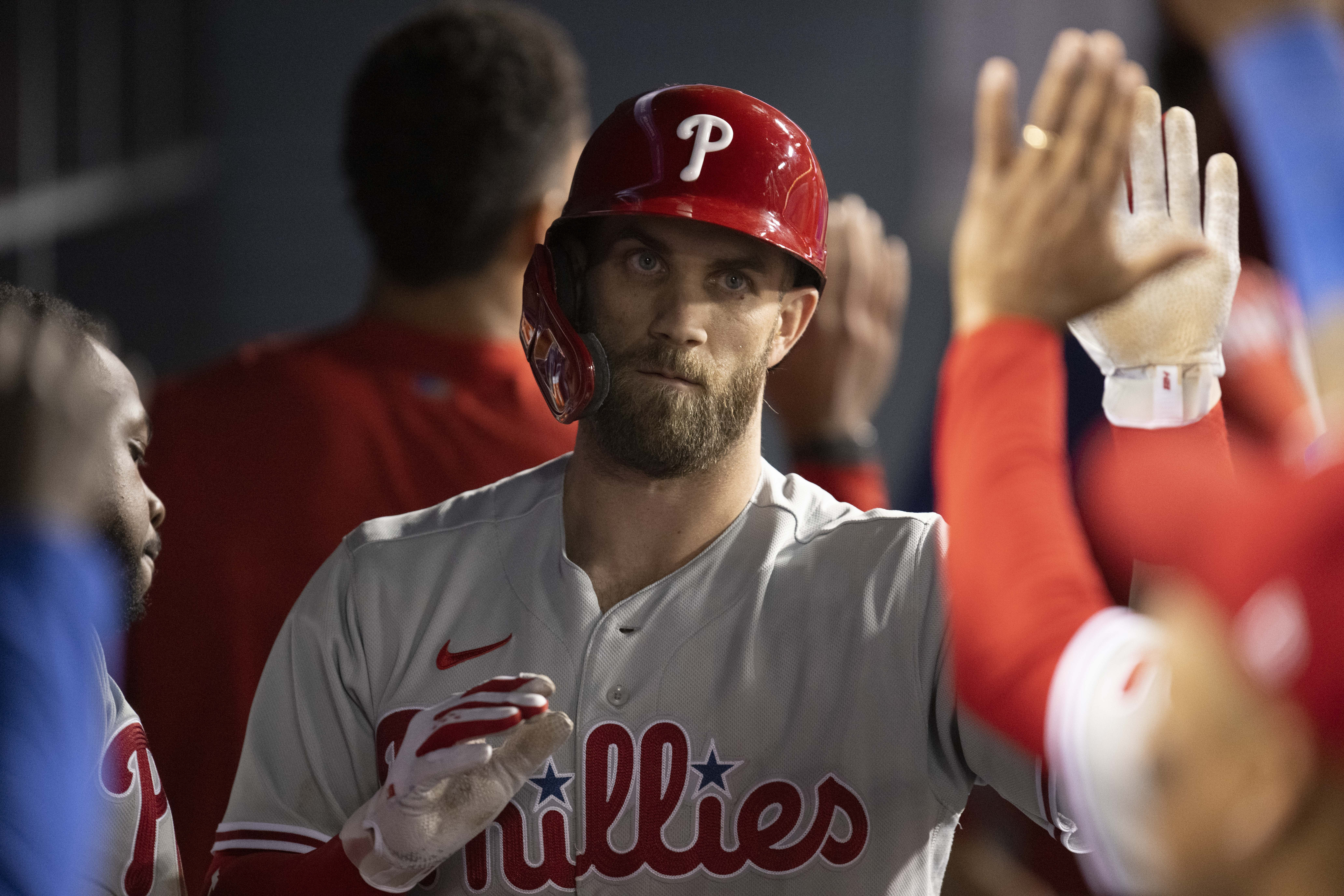Philadelphia Phillies' Bryce Harper is greeted in the dugout after hitting an RBI sacrifice fly during the ninth inning of the team's baseball game against the Los Angeles Dodgers in Los Angeles, Thursday, May 12, 2022.