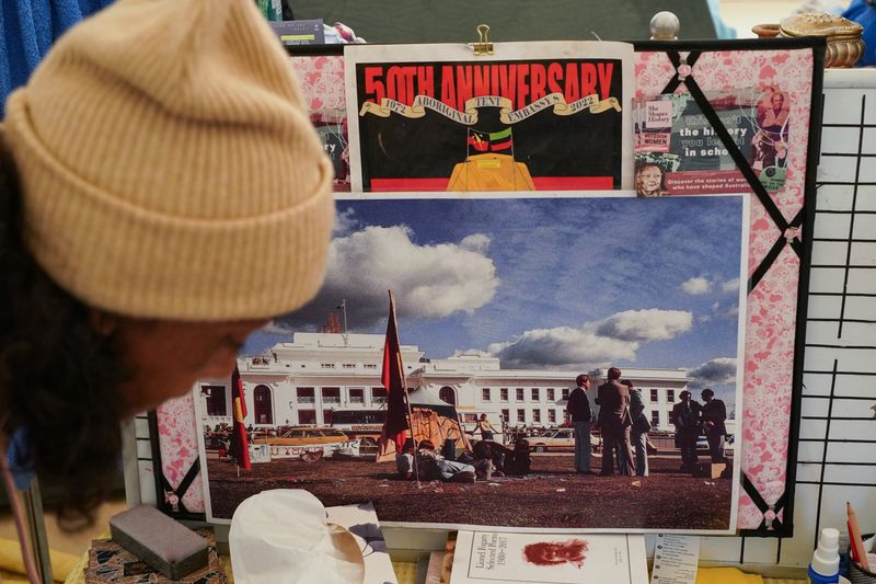 Gwenda Stanley, an Indigenous Australian of Gomeroi descent, organises belongings in front of a historical image of the Aboriginal Tent Embassy, a site of protest since 1972, at the same site in Canberra, Australia, May 4, 2022.
