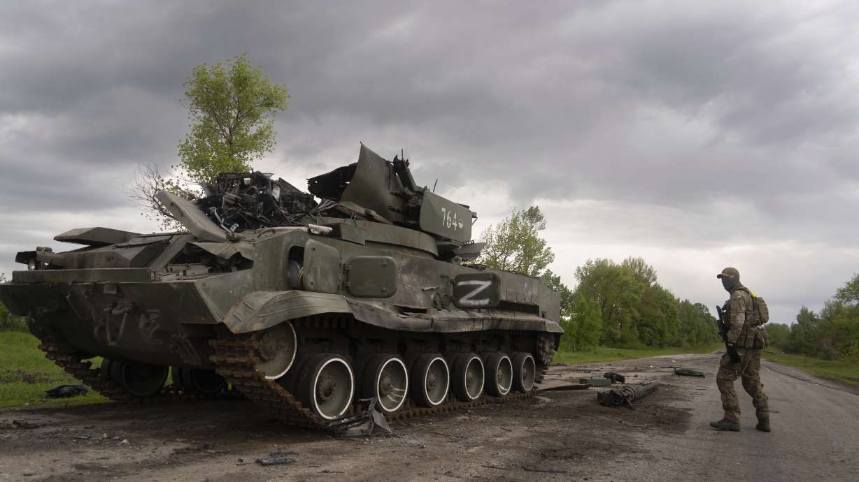 Ukrainian serviceman walks past a blown Russian APC near Kutuzivka, north of Kharkiv, east Ukraine, Sunday.