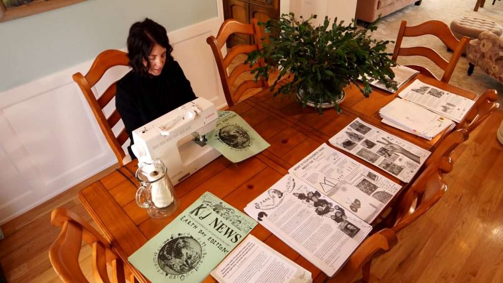 Jackie sews the newspaper.