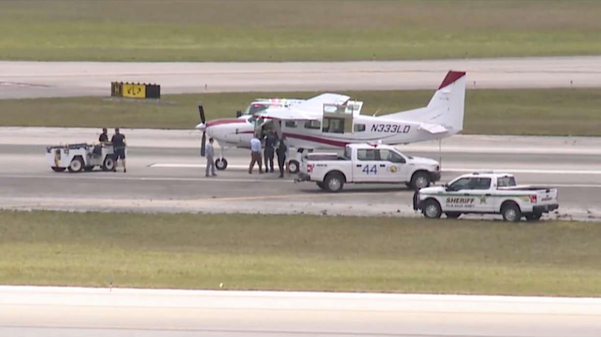 Emergency personnel surround a Cessna plane at Palm Beach International Airport on May 10 in West Palm Beach, Fla. A passenger with no flying experience was able to land the plane safely with help of air traffic controllers after the pilot was too sick to handle the controls.