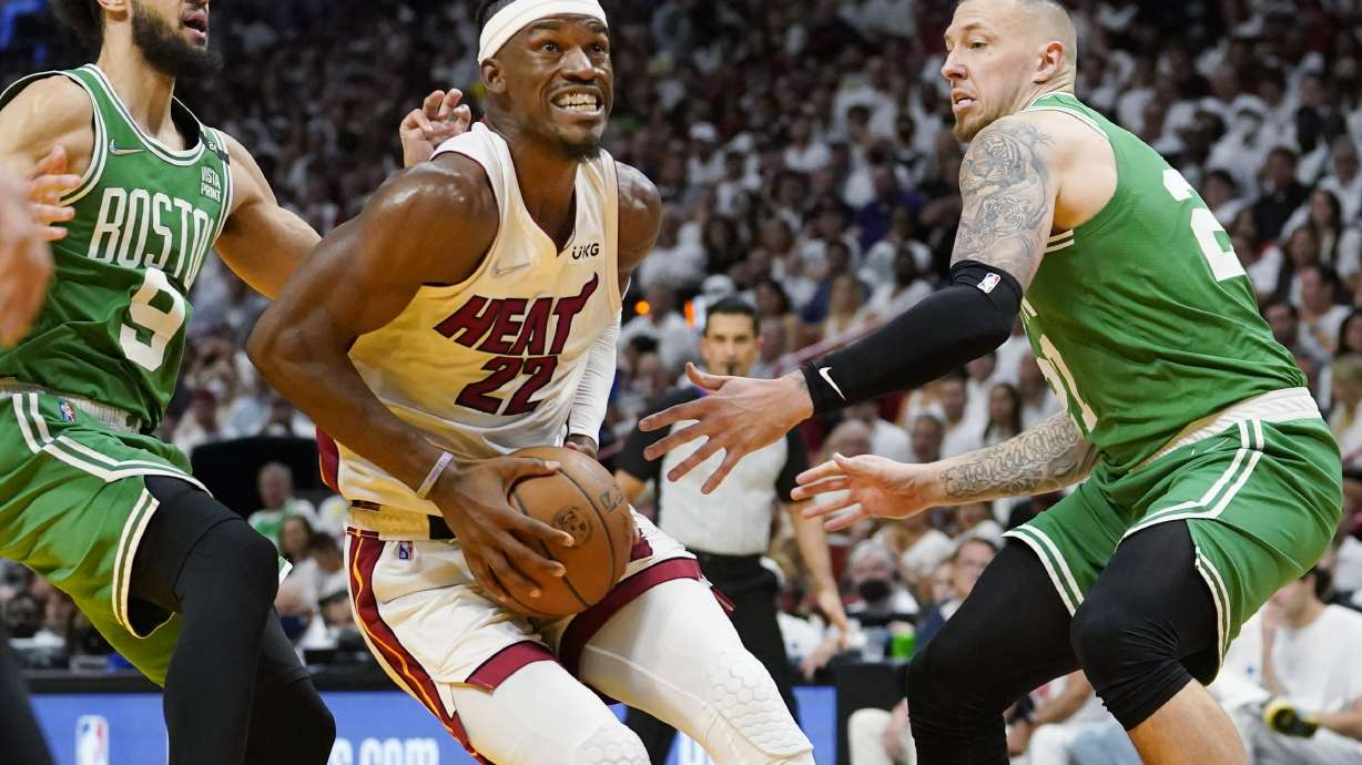 Miami Heat forward Jimmy Butler (22) drives to the basket between Boston Celtics guard Derrick White (9) and center Daniel Theis (27) during the second half of Game 1 of an NBA basketball Eastern Conference finals playoff series, Tuesday, May 17, 2022, in Miami.