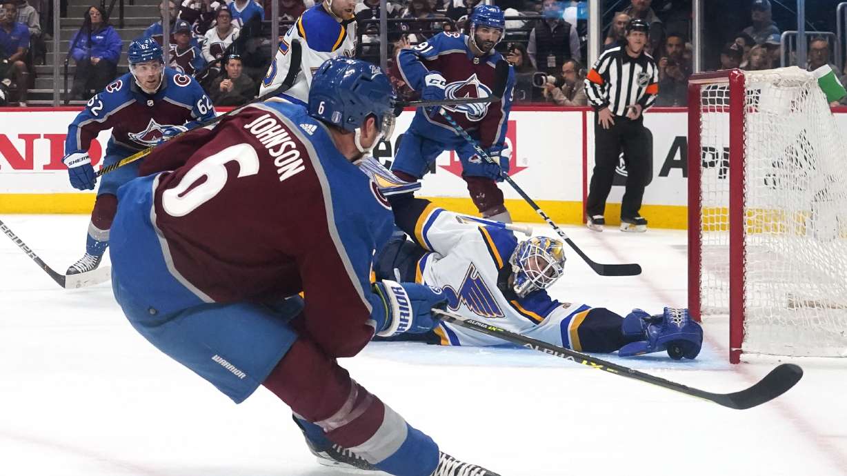 St. Louis Blues goaltender Jordan Binnington (50) makes a save against Colorado Avalanche defenseman Erik Johnson (6) during the second period in Game 1 of an NHL hockey Stanley Cup second-round playoff series Tuesday, May 17, 2022, in Denver.