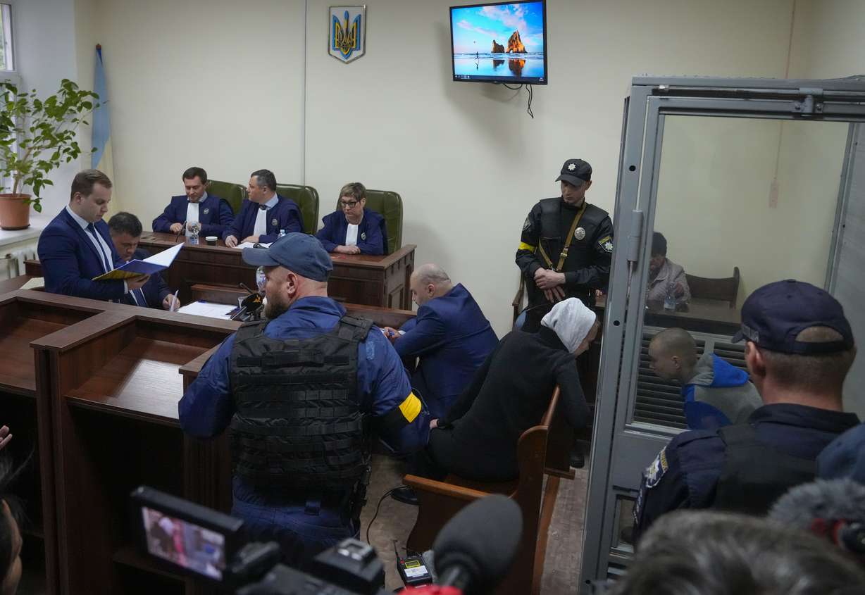 Sitting behind a glass, Russian army Sergeant Vadim Shishimarin, 21, talks with his translator, center right, during a court hearing in Kyiv, Ukraine, Wednesday.