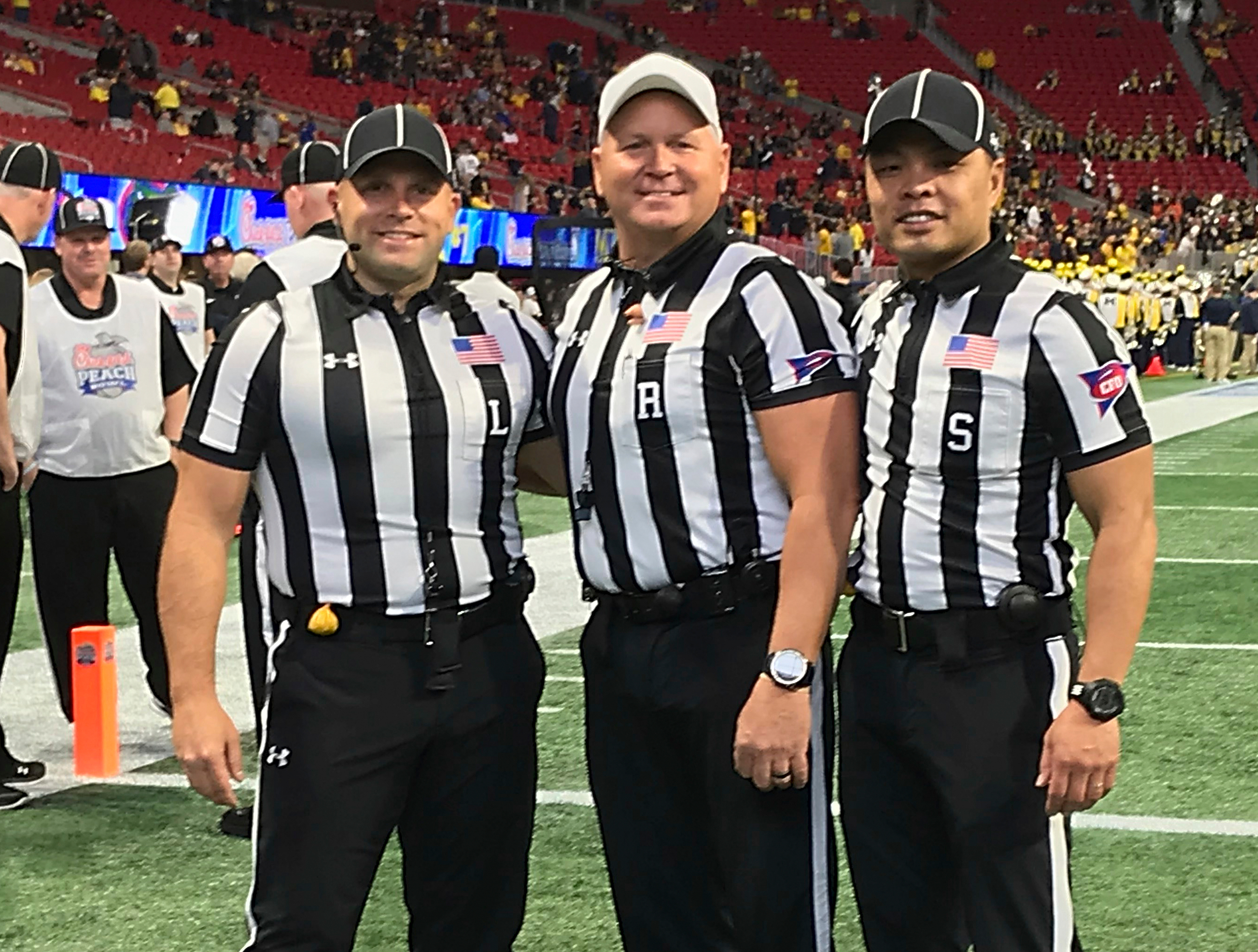 In this Dec. 29, 2018 photo provided by Lo van Pham, from left, line judge Derek Anderson,  referee Mike Defee and side judge Lo van Pham pose for a photo before the Peach Bowl NCAA college football game in Atlanta. Lo van Pham’s journey to the NFL began when he fell in love with sports upon arriving in Texas after living in refugee camps with his family. More than 40 years later, van Pham is set to become the first Asian American to officiate in the NFL. 