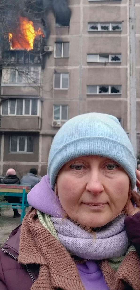 Anzhela Kumurxhi takes a selfie as her apartment building burns in the background in Mariupol, Ukraine.