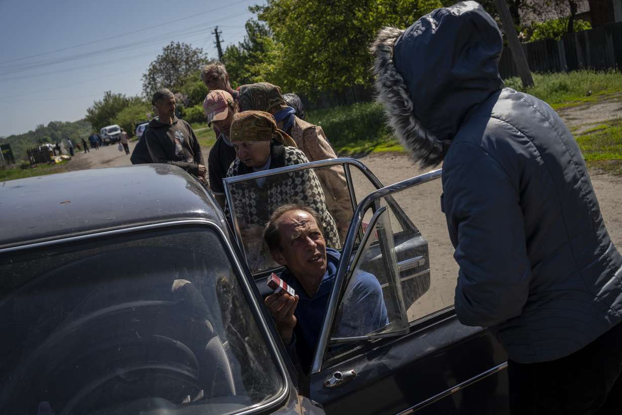Villagers queue to buy cigarettes and bread from a peddler in the village of Staryi Saltiv, east Kharkiv, Ukraine, Friday. The village formerly occupied by Russian forces is back under Ukrainian control, albeit very close to the front line and under constant shelling.