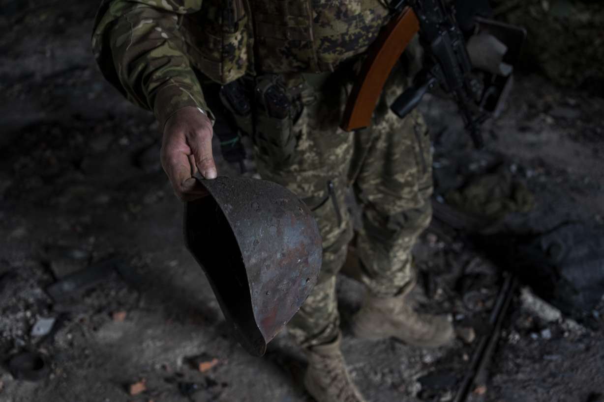 A Ukrainian serviceman holds the helmet used by Russian troops inside a school damaged during a battle between Russian and Ukrainian forces in the village of Vilkhivka, on the outskirts of Kharkiv, in eastern Ukraine, Friday.