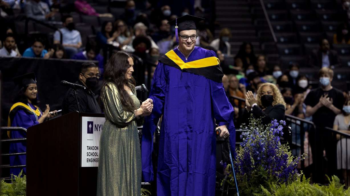 Ellis Brown helps her husband, Spencer, walk across the stage to receive his diploma during his commencement ceremony from New York University’s Tandon School of Engineering at the Barclays Center in Brooklyn, N.Y., on Monday, May 16.