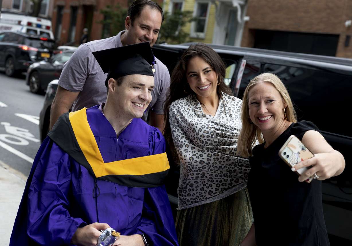Friends Kyle and Melissa DeMordaunt, back left, and front right, take photos with Spencer and Ellis Brown before Spencer’s commencement ceremony from New York University’s Tandon School of Engineering at the Barclays Center in Brooklyn, N.Y., on Monday, May 16. The DeMordaunts helped get Spencer around the city and cared for the Browns’ baby so that Ellis could help Spencer walk across stage to receive his diploma.