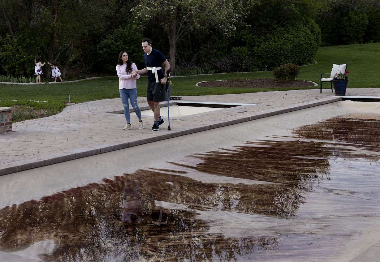 Ellis Brown helps her husband, Spencer, walk a lap around the swimming pool of her parents’ home in Alpine on Thursday, May 5. Spencer Brown injured his spinal cord last July after diving into the swimming pool and hitting his head on the bottom during his graduation party.