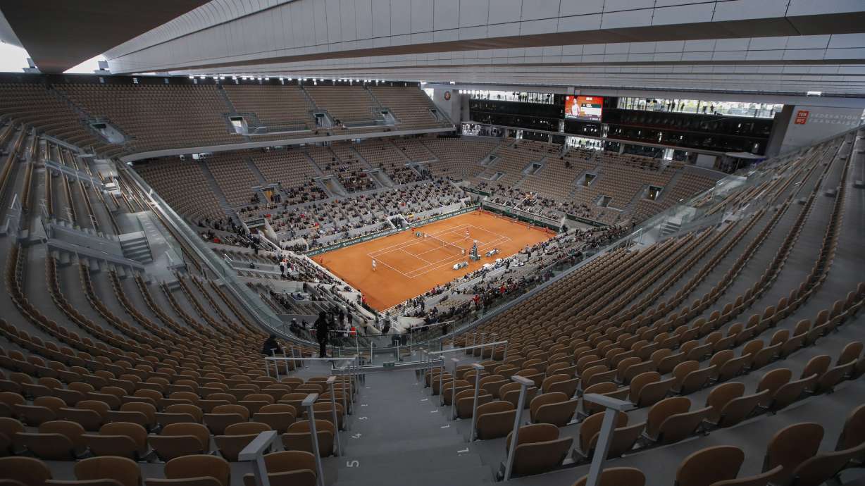 FILE - Rows of empty seats are seen at centre court at the Roland Garros stadium in Paris Sunday, Oct. 11, 2020, as Serbia's Novak Djokovic and Spain's Rafael Nadal warm up for the final match of the French Open tennis tournament. All COVID-19 related restrictions have been lifted and crowds are expected to fill the stadium.