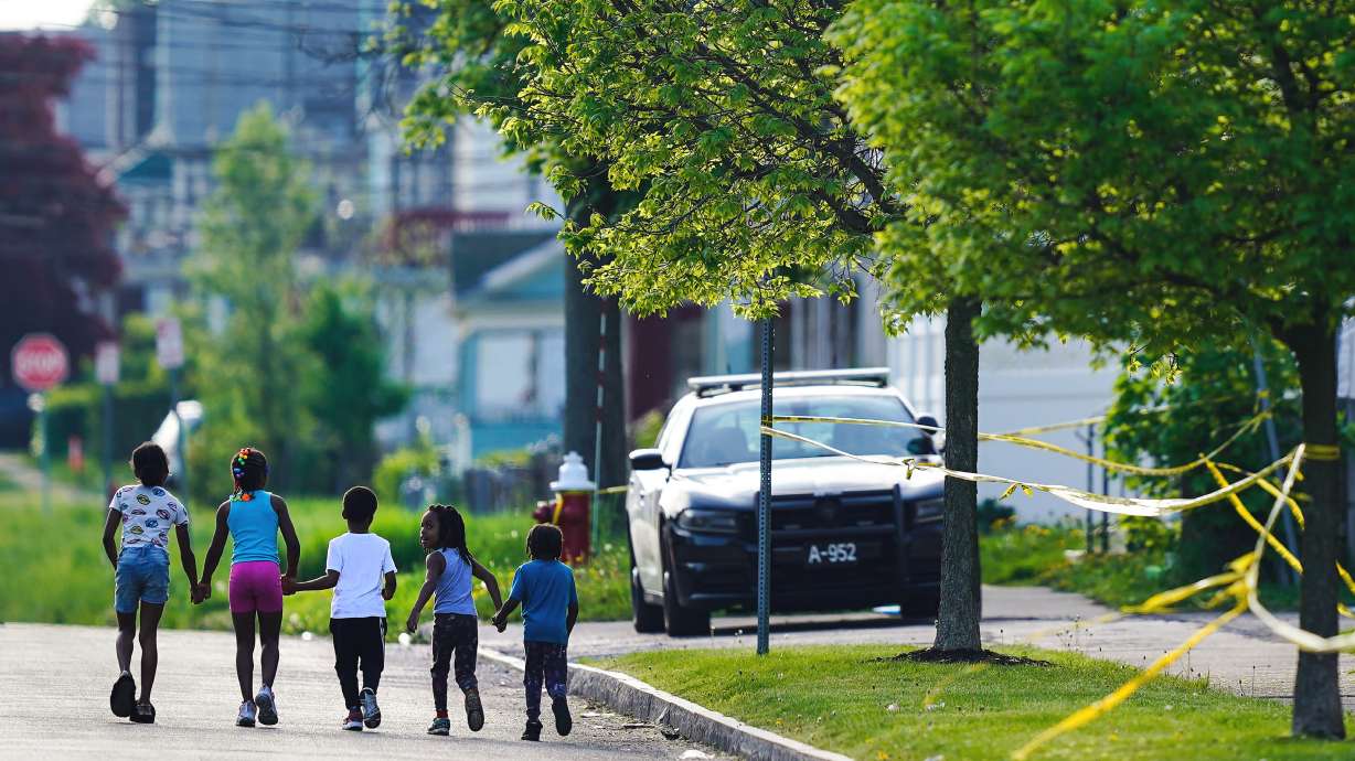 Children walk hand-in-hand near the scene of a shooting at a supermarket in Buffalo, N.Y., May 15. The shooting rampage at a Buffalo supermarket, carried out by an 18-year-old who was flagged for making a threatening comment at his high school the year before, highlights concerns over whether schools are adequately supporting and screening students.