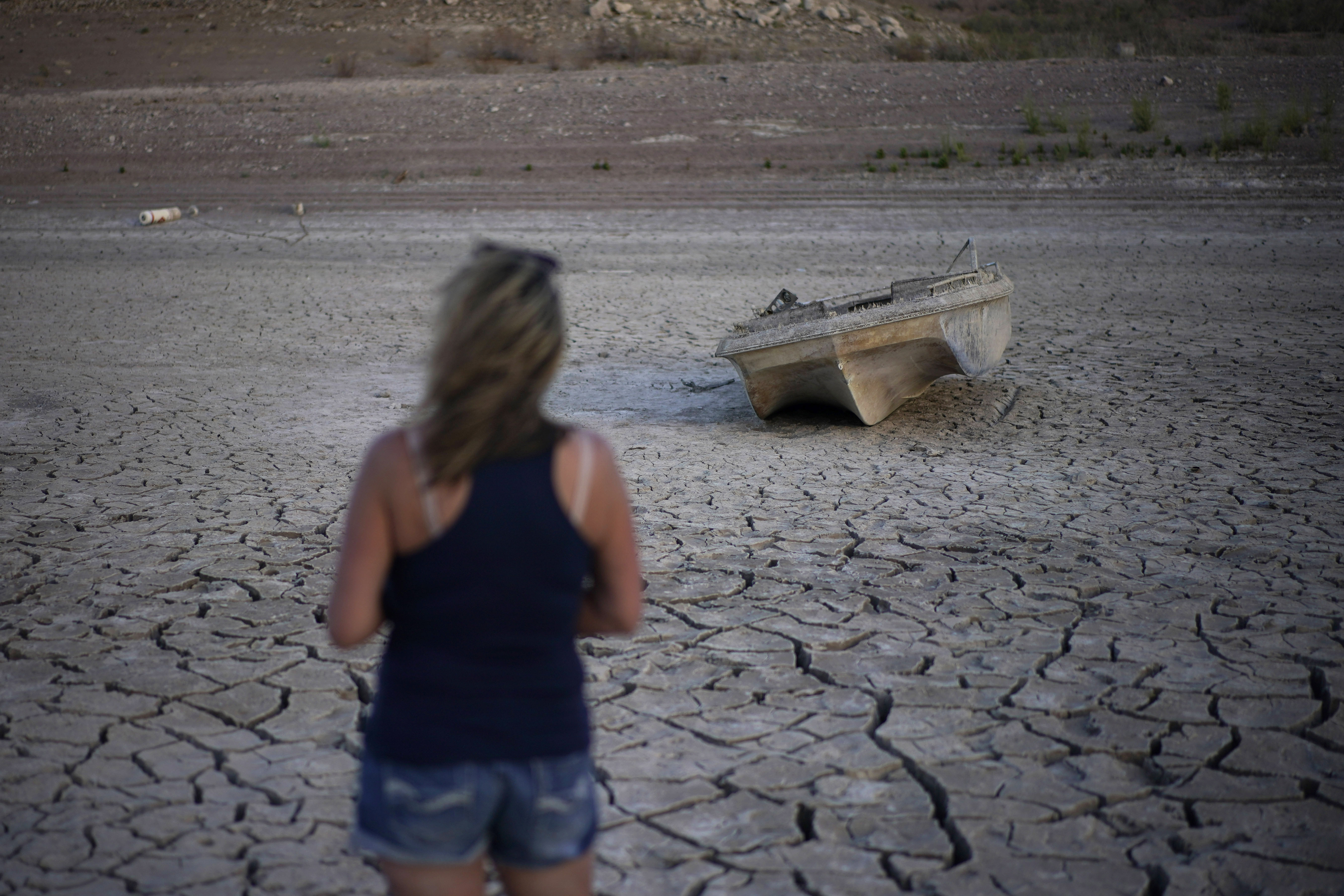 Misha McBride looks at a formerly sunken boat now on cracked earth hundreds of feet from what is now the shoreline on Lake Mead at the Lake Mead National Recreation Area, May 9, near Boulder City, Nev.