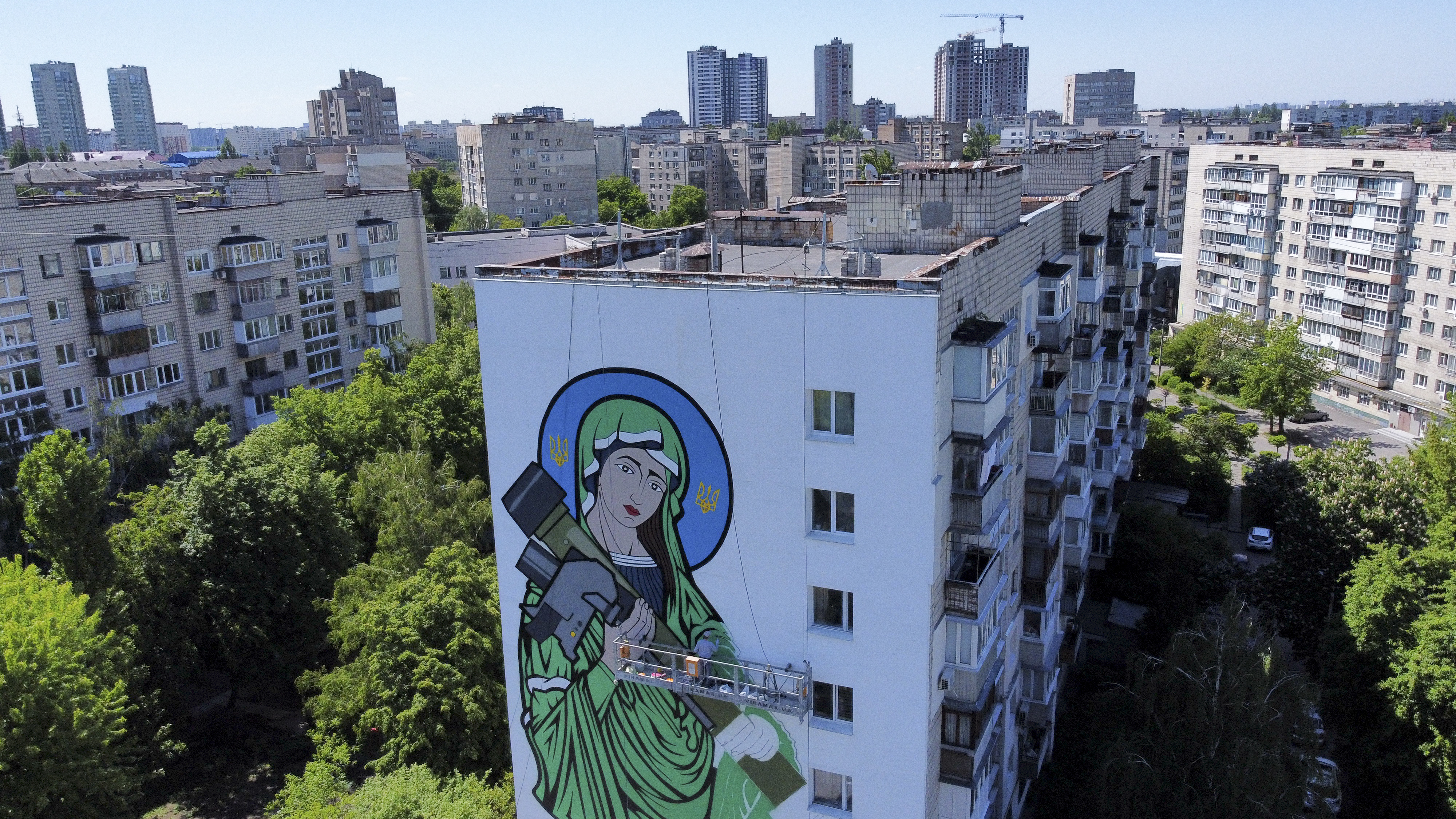 A worker paints a "Saint Javelin," a Virgin Mary holding an American-made anti-tank missile, in Kyiv, Ukraine, Tuesday. No matter where they live, the 3-month-old war never seems to be far away for Ukrainians.