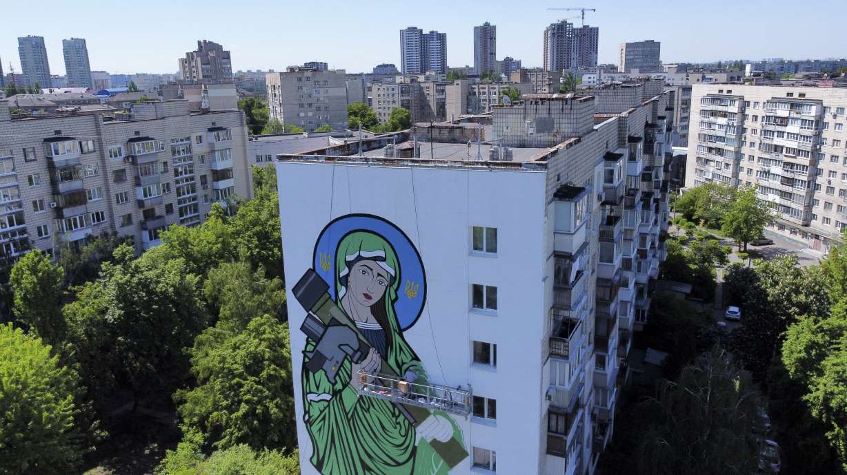 A worker paints a "Saint Javelin," a Virgin Mary holding an American-made anti-tank missile, in Kyiv, Ukraine, Tuesday. No matter where they live, the 3-month-old war never seems to be far away for Ukrainians.