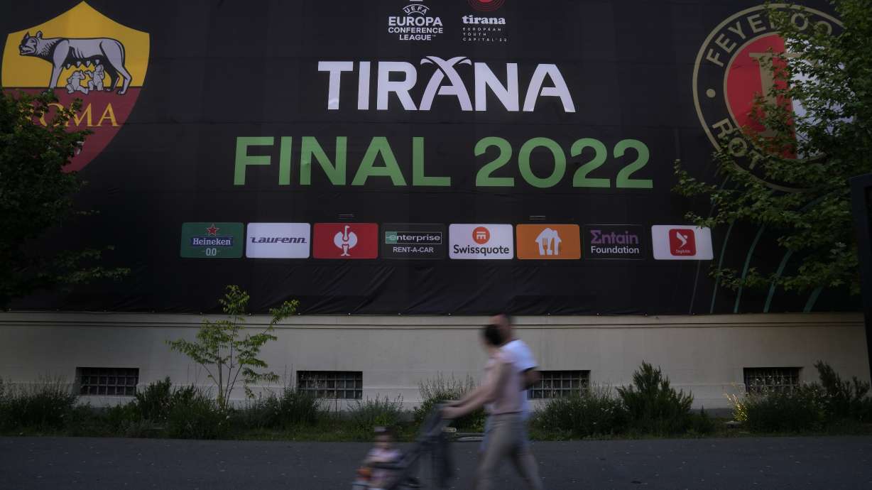 People walk past a Europa Conference League poster, in downtown of Tirana, Albania, Tuesday, May 24, 2022. Feyenoord will play Roma Wednesday in the Europa Conference League Final.