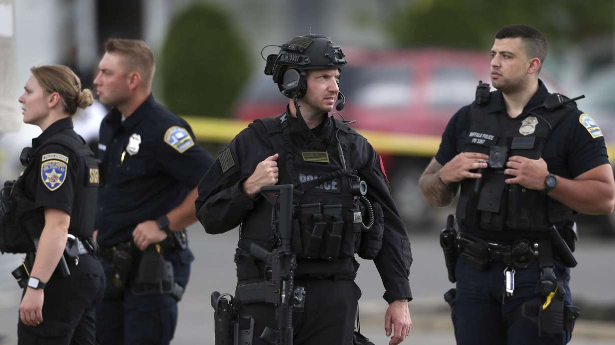 Police walk along the perimeter of the scene after a shooting at a supermarket on May 14, in Buffalo, N.Y. Officials said the gunman entered the supermarket with a rifle and opened fire. Investigators believe the man may have been livestreaming the shooting and were looking into whether he had posted a manifesto online.
