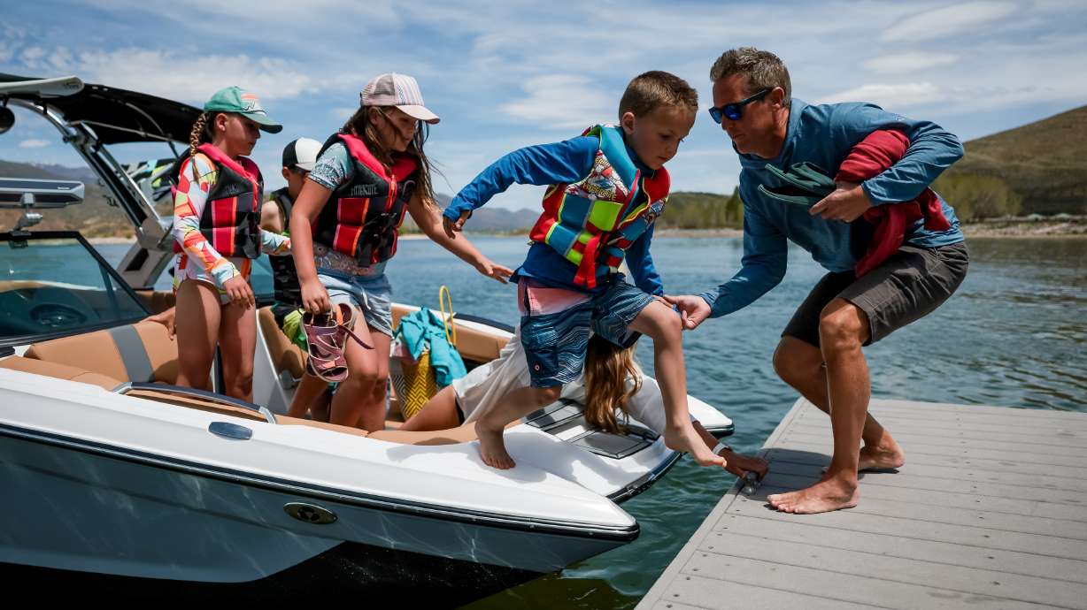Jonathan Wagstaff, owner of Deer Creek Island Resort, right, helps Gabe Allen, 5, off a rental boat at the resort in Heber City on Thursday. Also on the boat are Madeline Allen, 9, Kaden Allen, 11, Evelyn Allen, 9, and their mother, Alise Allen, left to right.