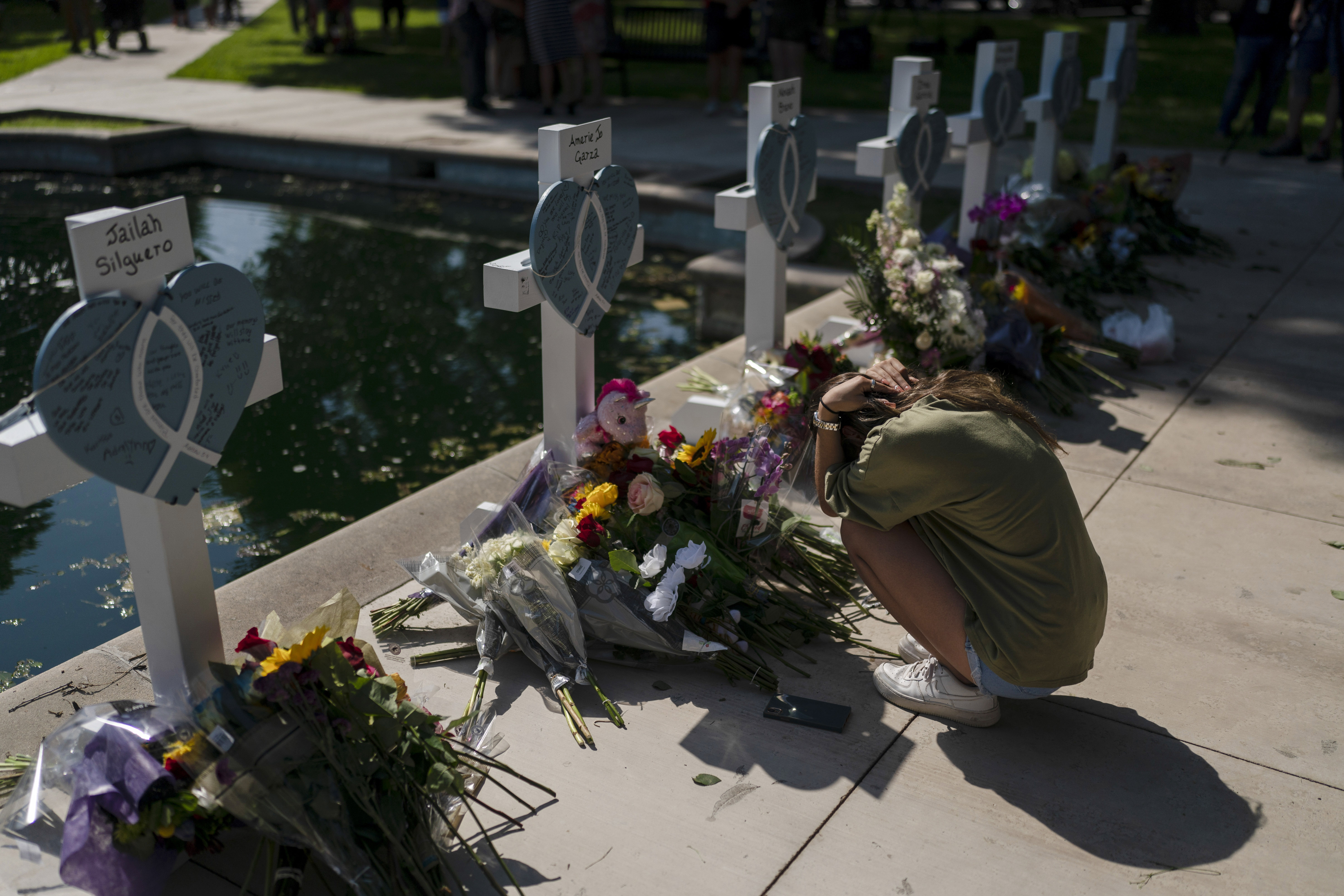 Elena Mendoza, 18, grieves in front of a cross honoring her cousin, Amerie Jo Garza, one of the victims killed in this week's elementary school shooting in Uvalde, Texas, Thursday. Fourth-grade teacher Irma Garcia was killed in her Texas classroom on Tuesday, massacred along with her co-teacher and 19 students. Two days later, a family member says her brokenhearted husband died.